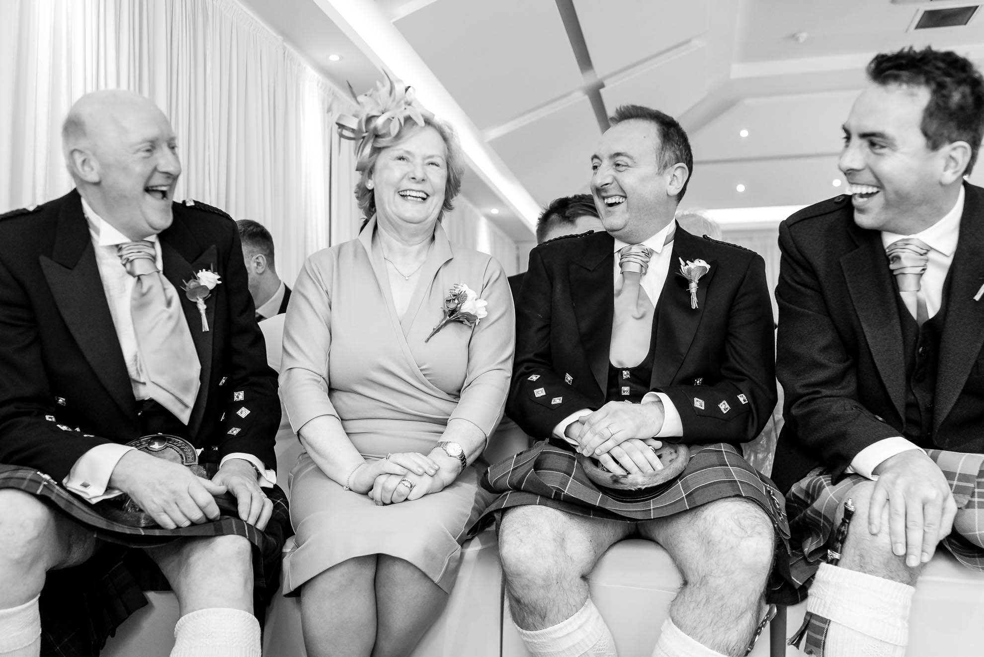Mother and father of the groom share a joke with the ushers