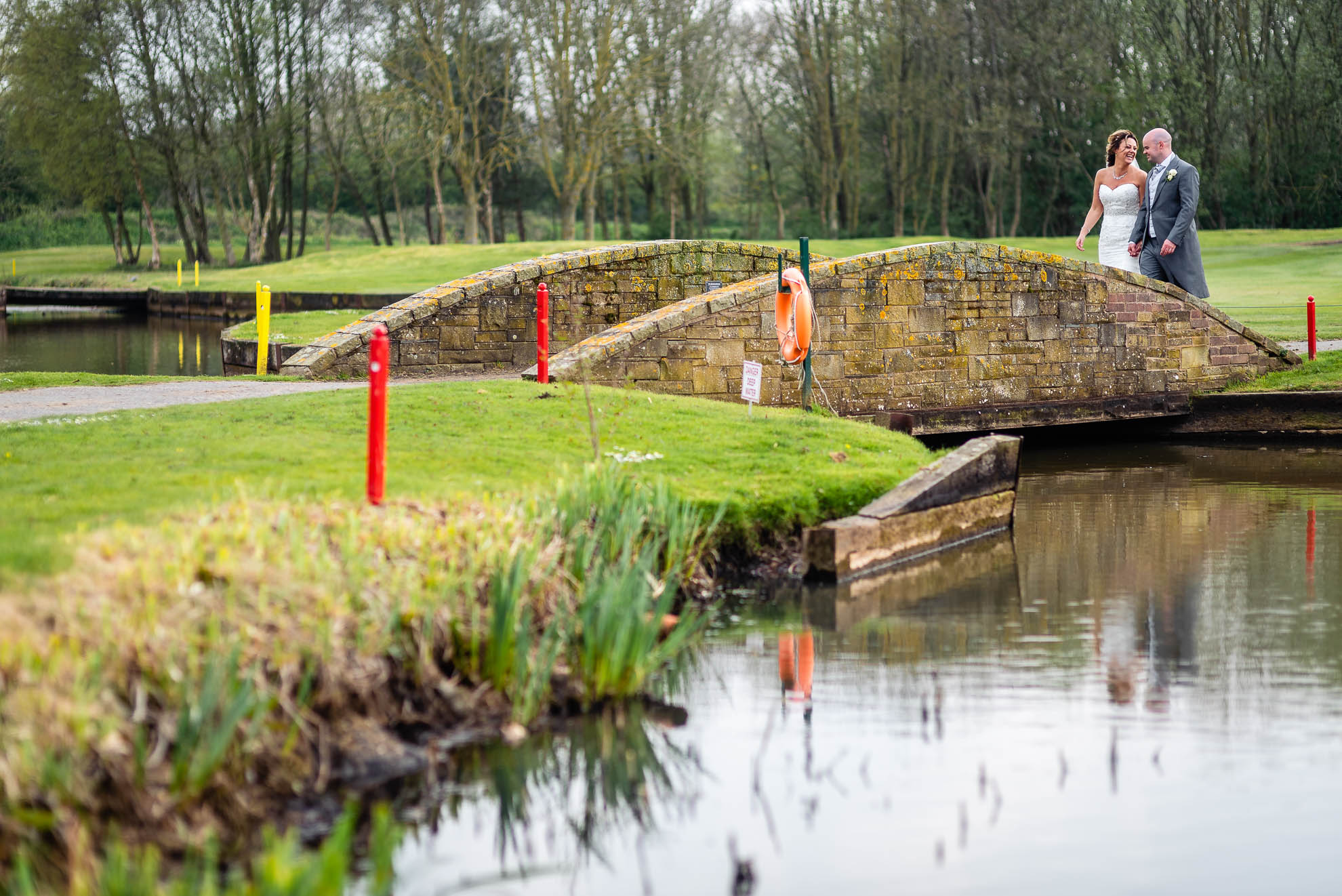 Bride and groom walk towards a bridge