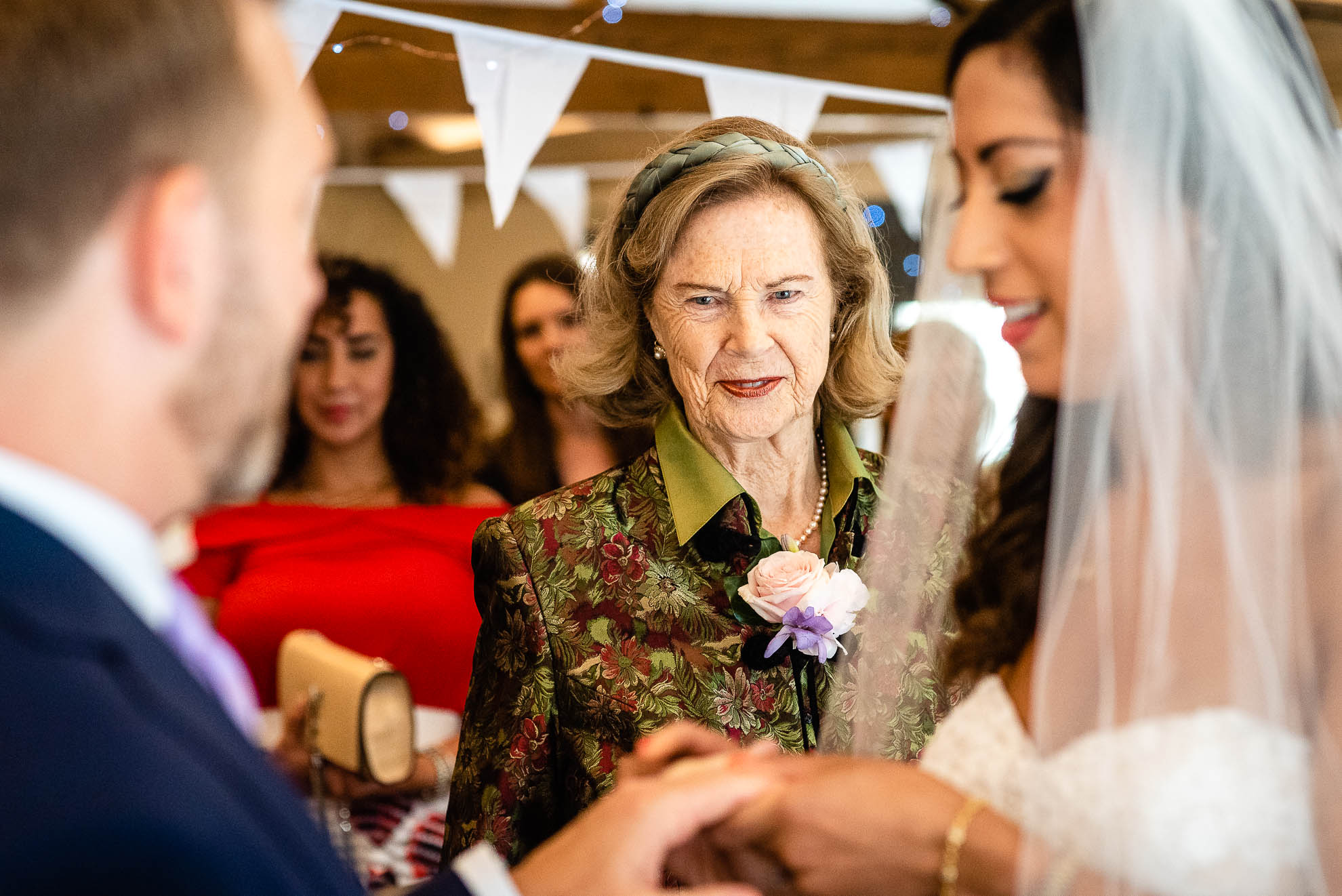 Mother of the bride looks on during the exchange of rings