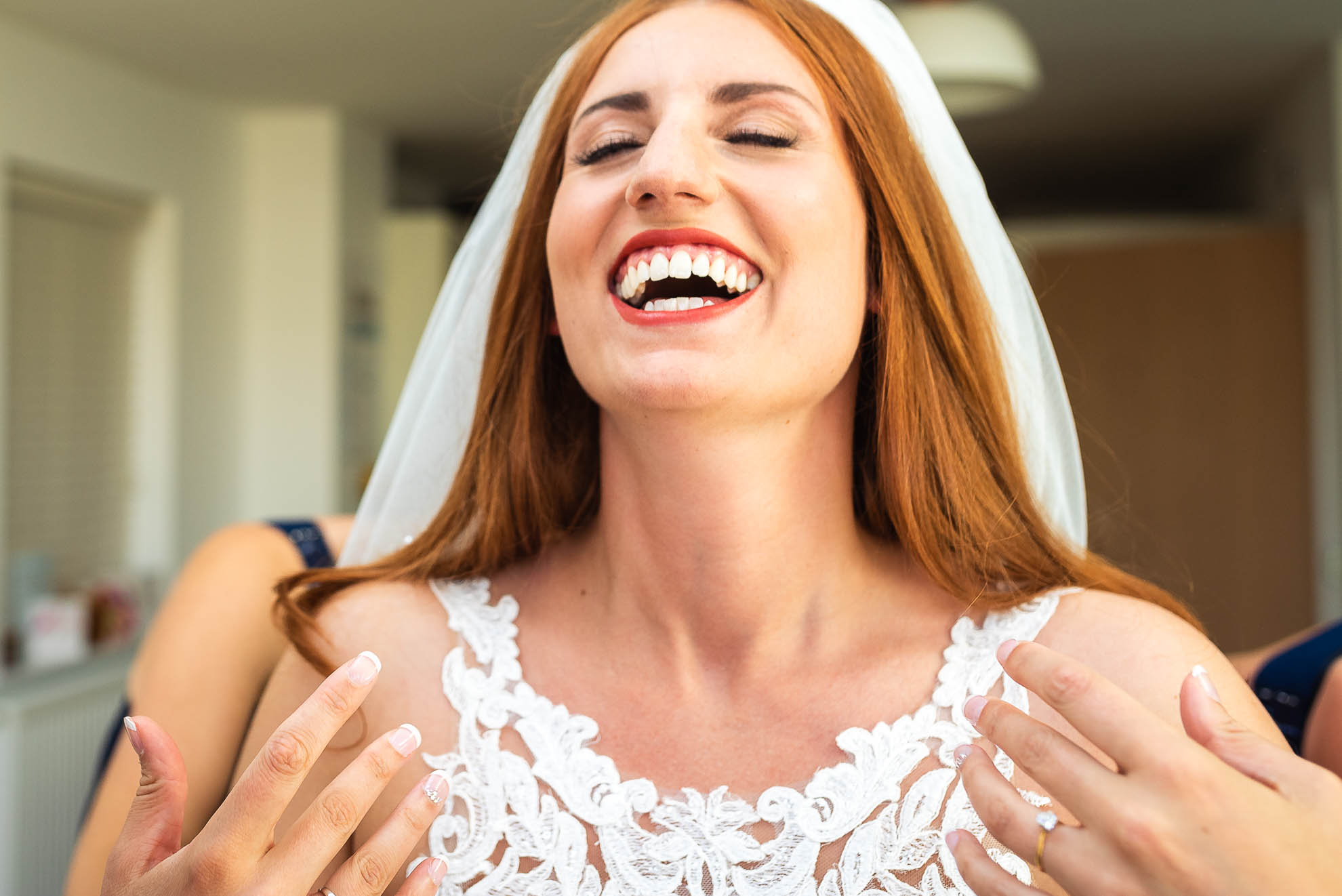 Bride laughs in delight as she puts her dress on