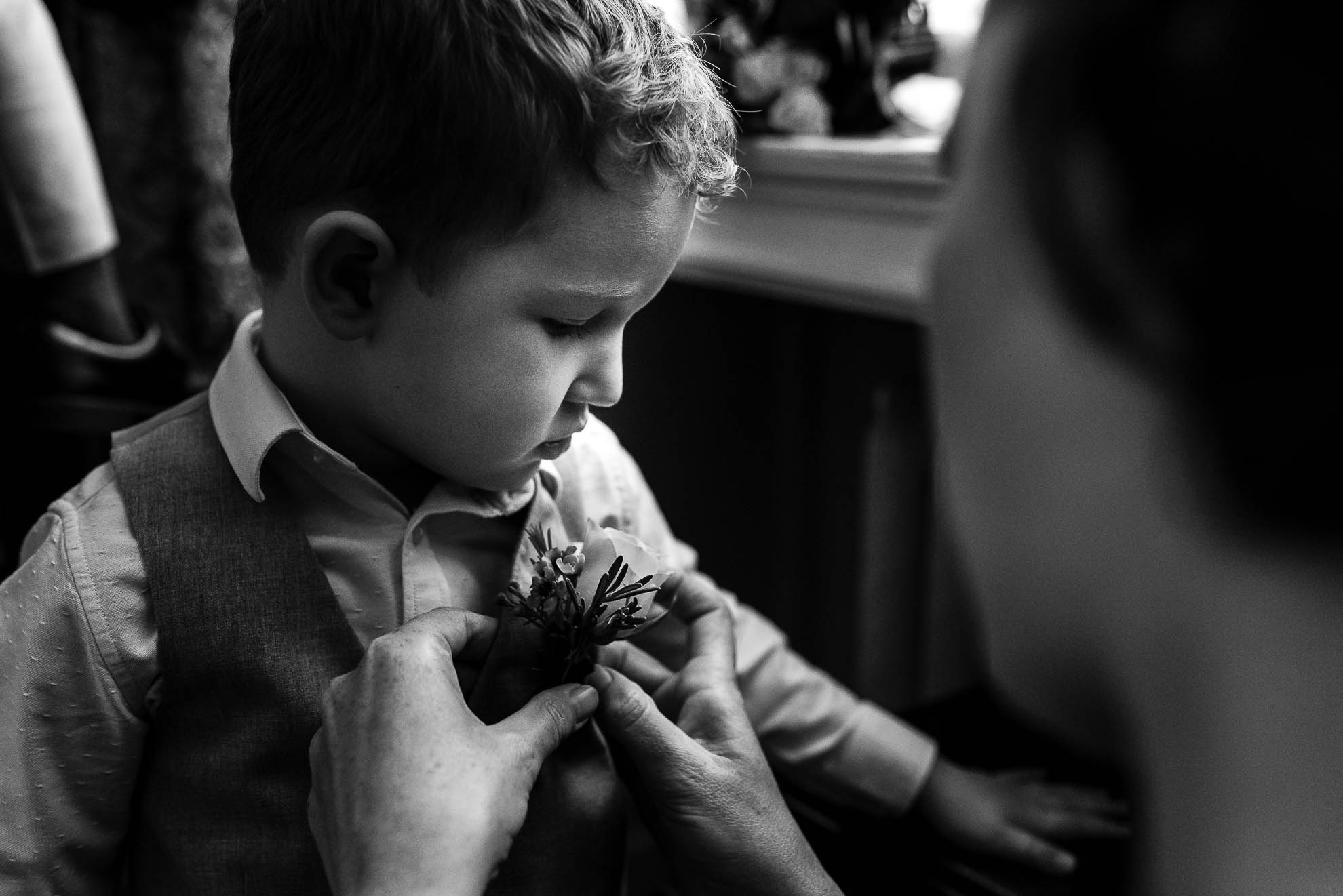 Bridesmaid puts flower on page boys lapel