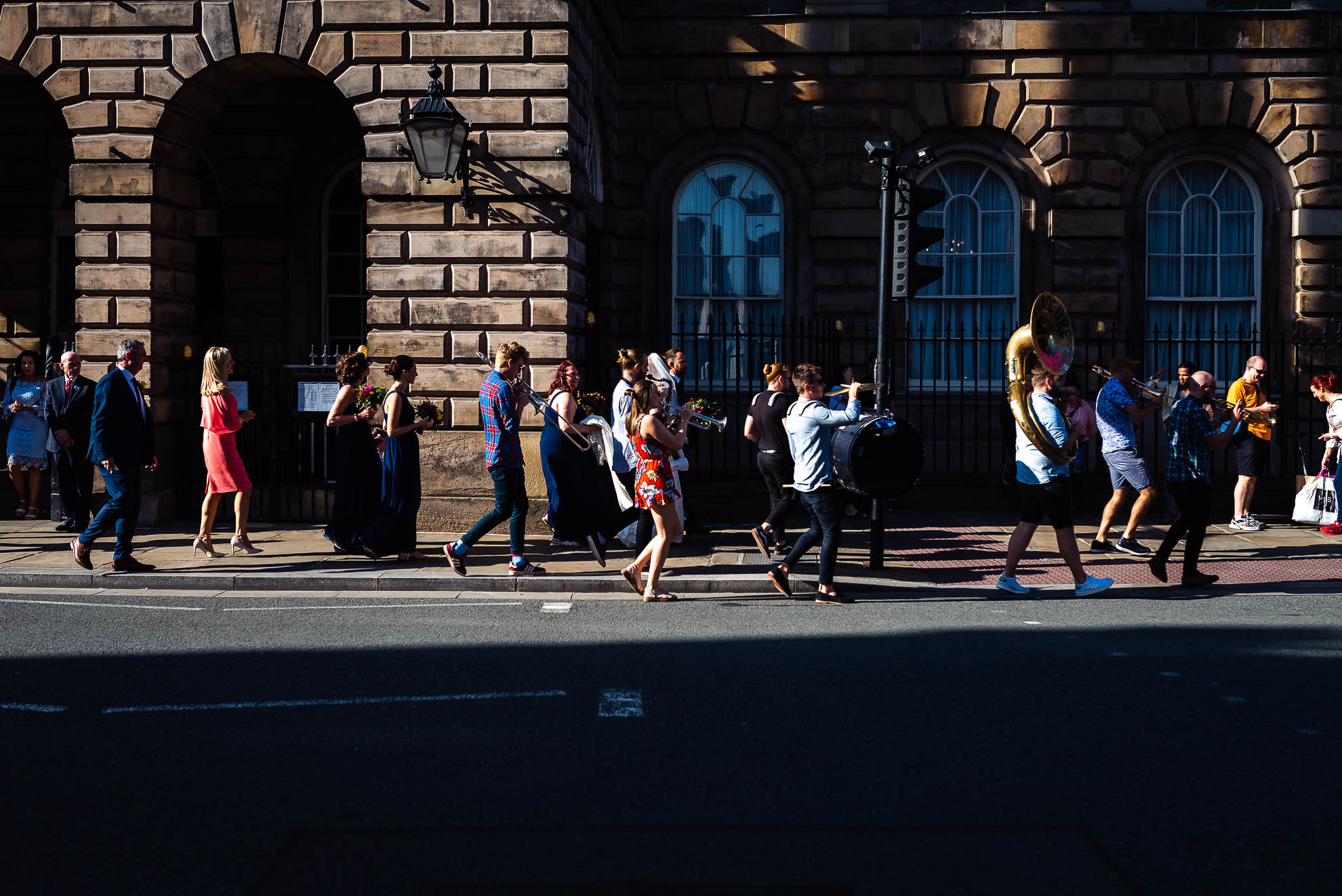 Wedding party walking along street with a brass band