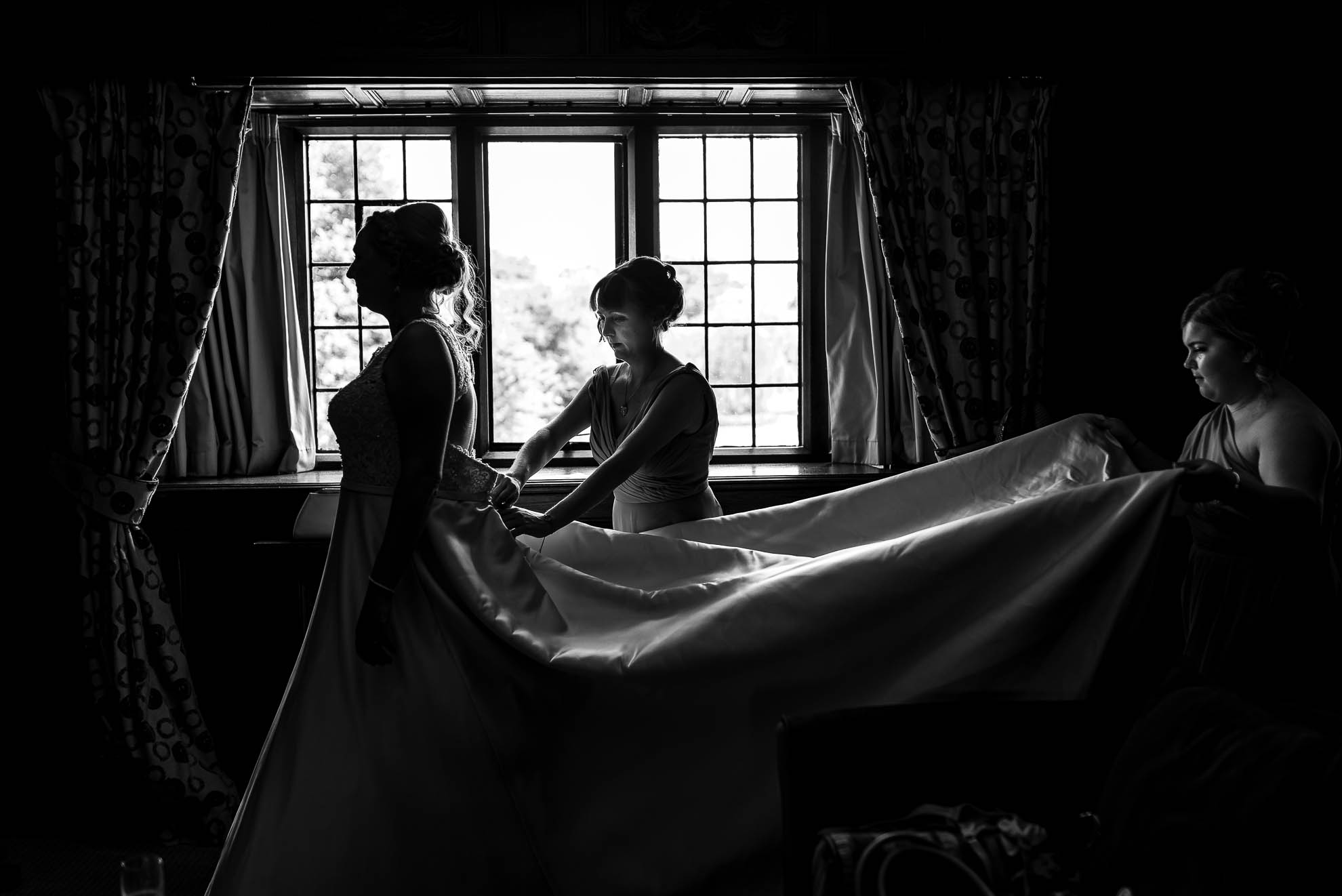Bride being helped into her dress by her bridesmaids