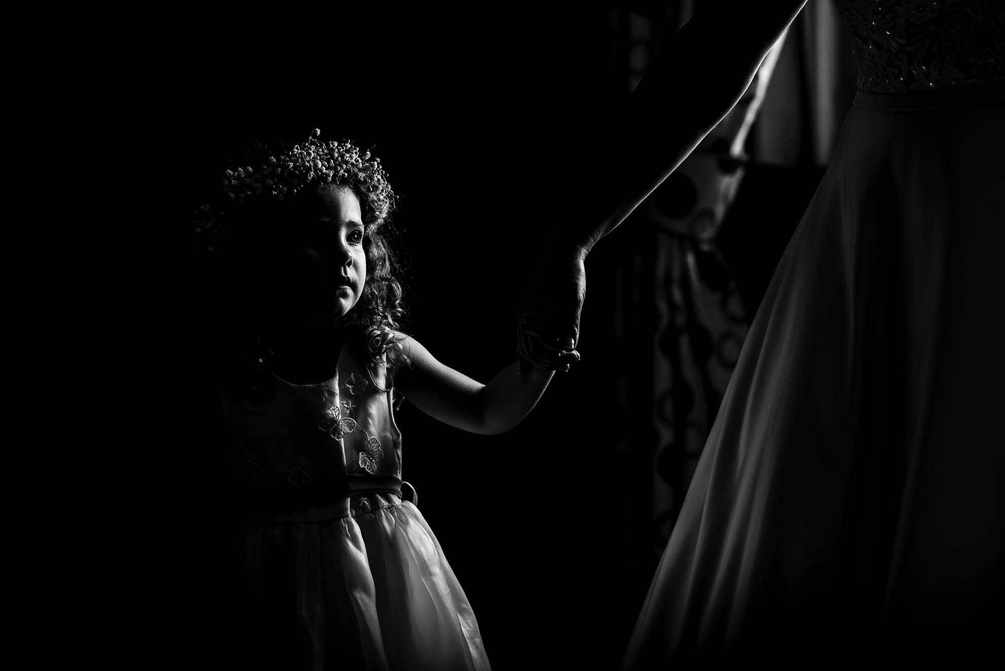 Little flower girl holding brides hand