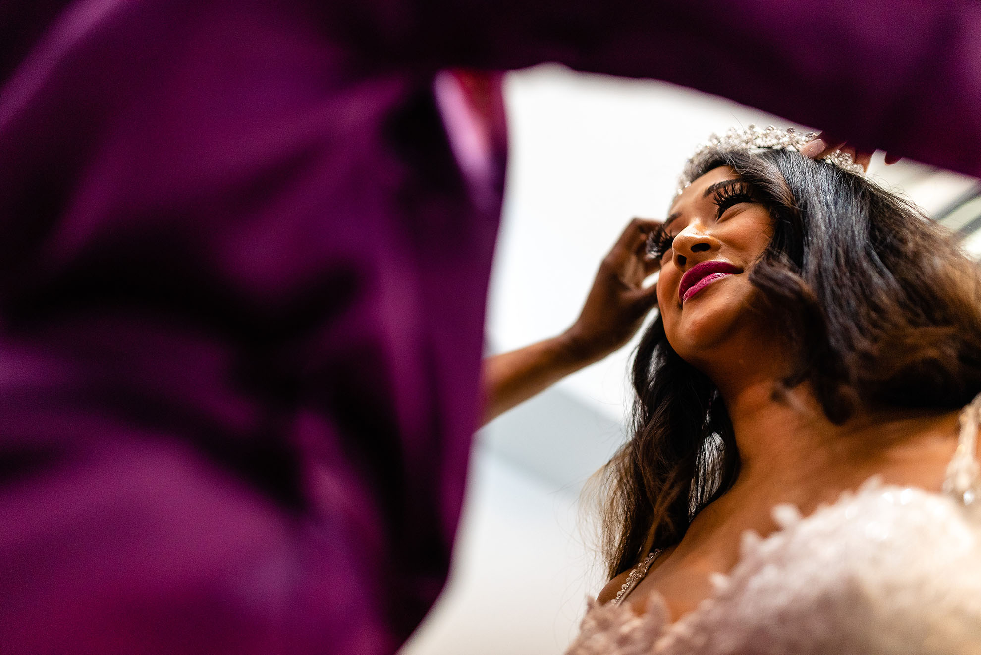 Bridesmaid places tiara on brides head