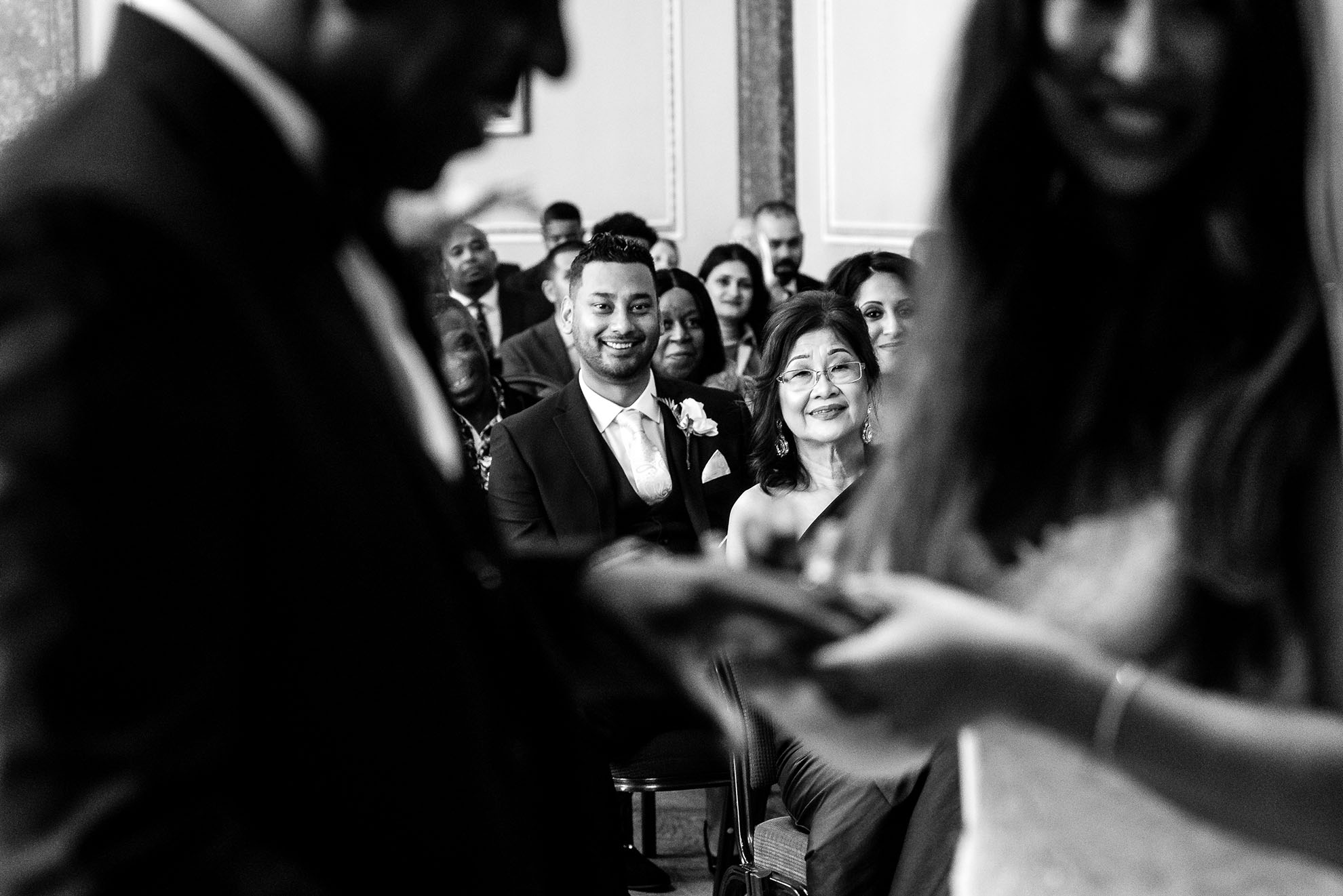Mother of the bride and brother watch the exchange of rings