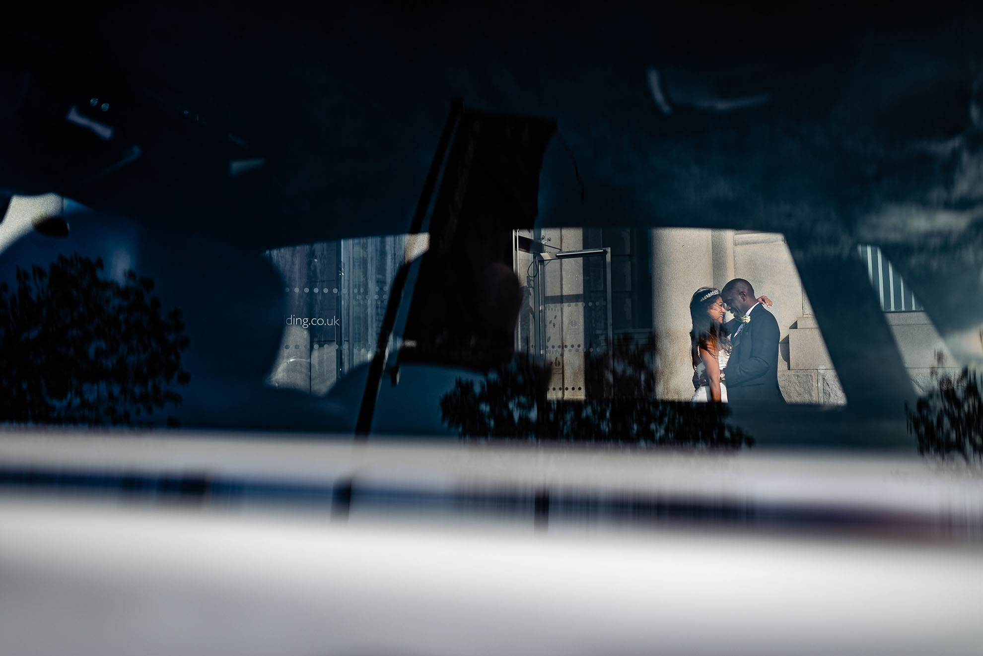 Bride and groom portrait through wedding car window