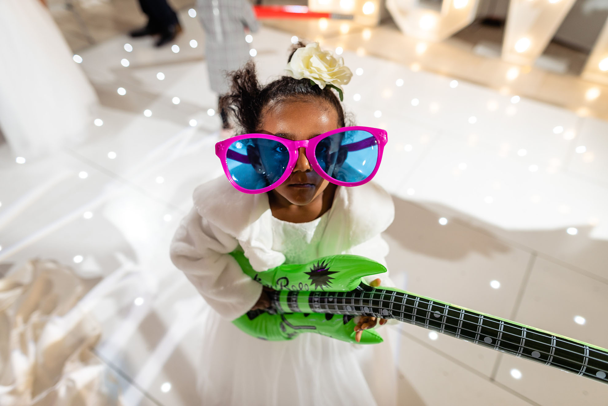 Flower girl with toy guitar and huge sunglasses