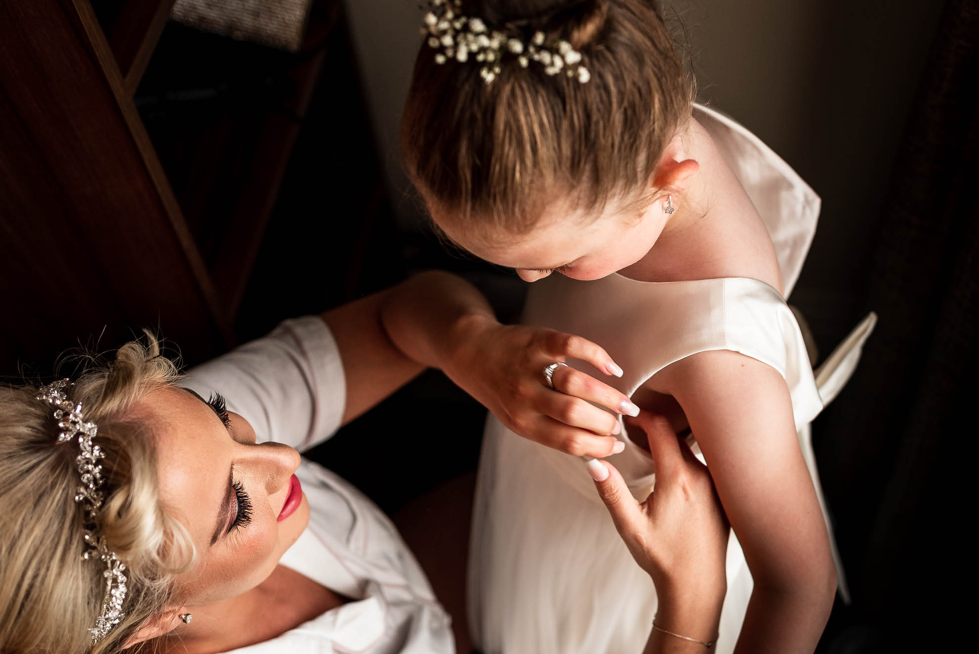 Bride helps her daughter into her dress