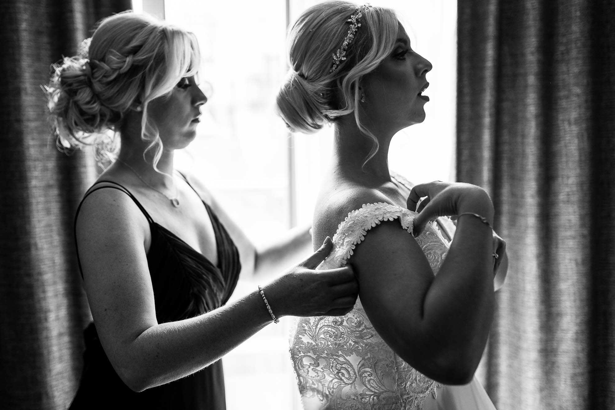 Bridesmaid helps bride into her dress