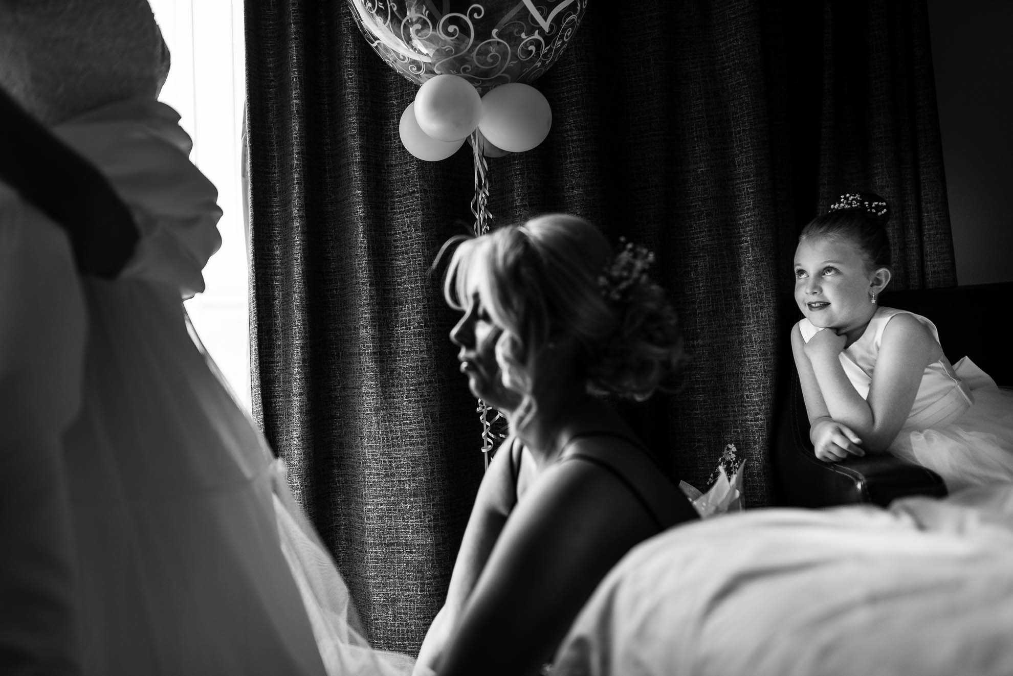 Brides daughter watches her mum put on her wedding dres