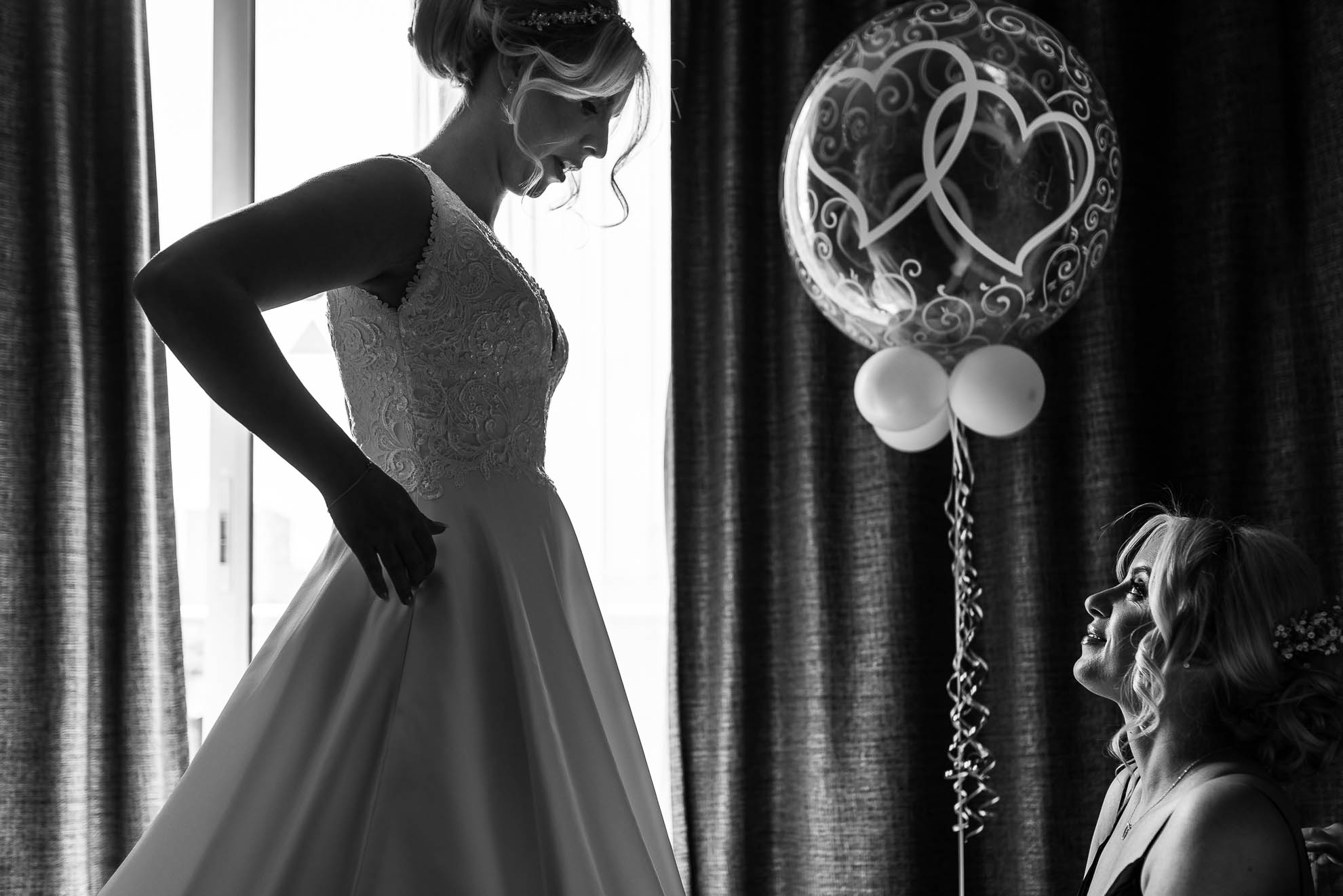 Bridesmaid smiles as she looks at the bride in her wedding dress