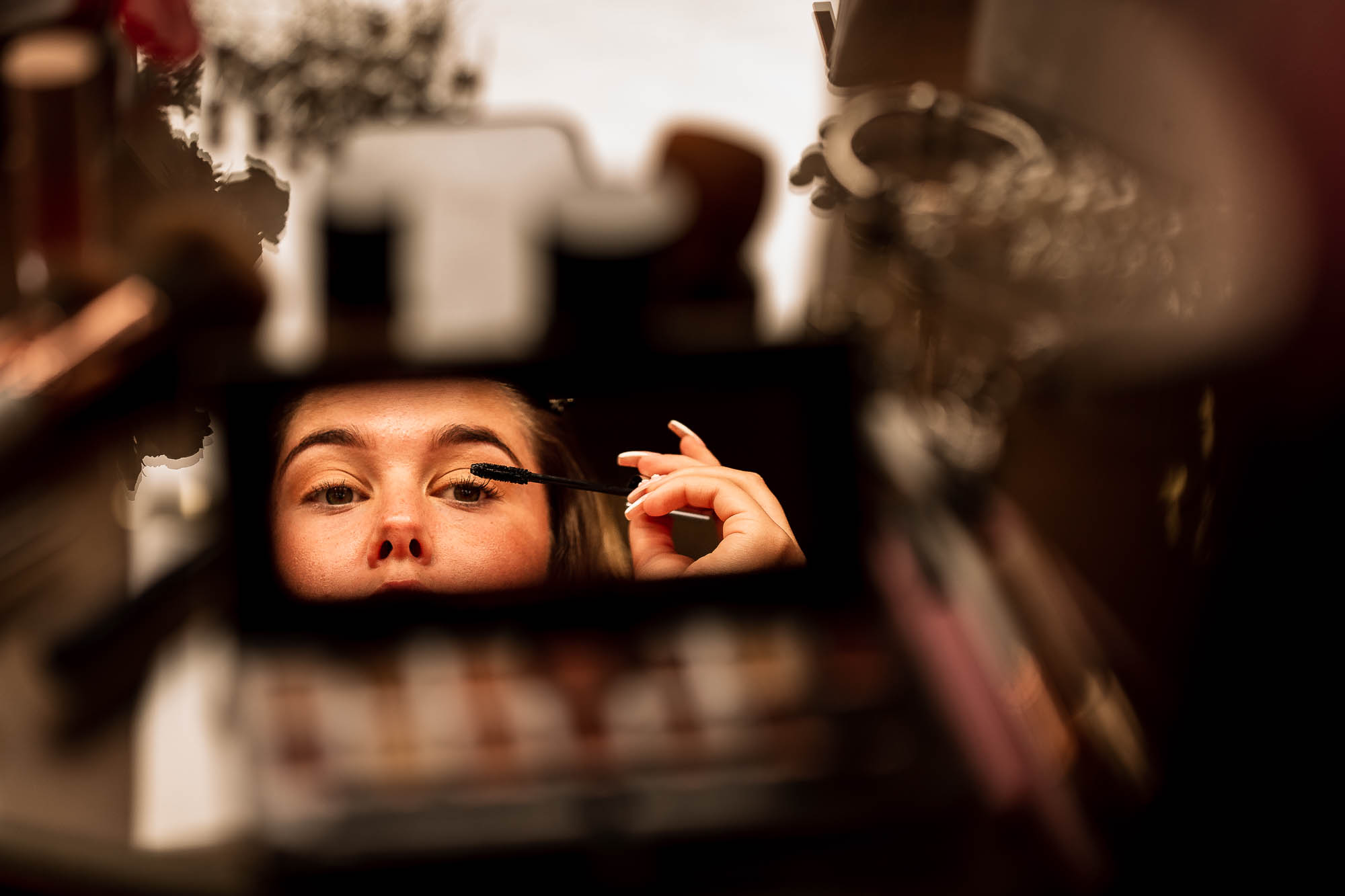 Bride applies make up in mirror