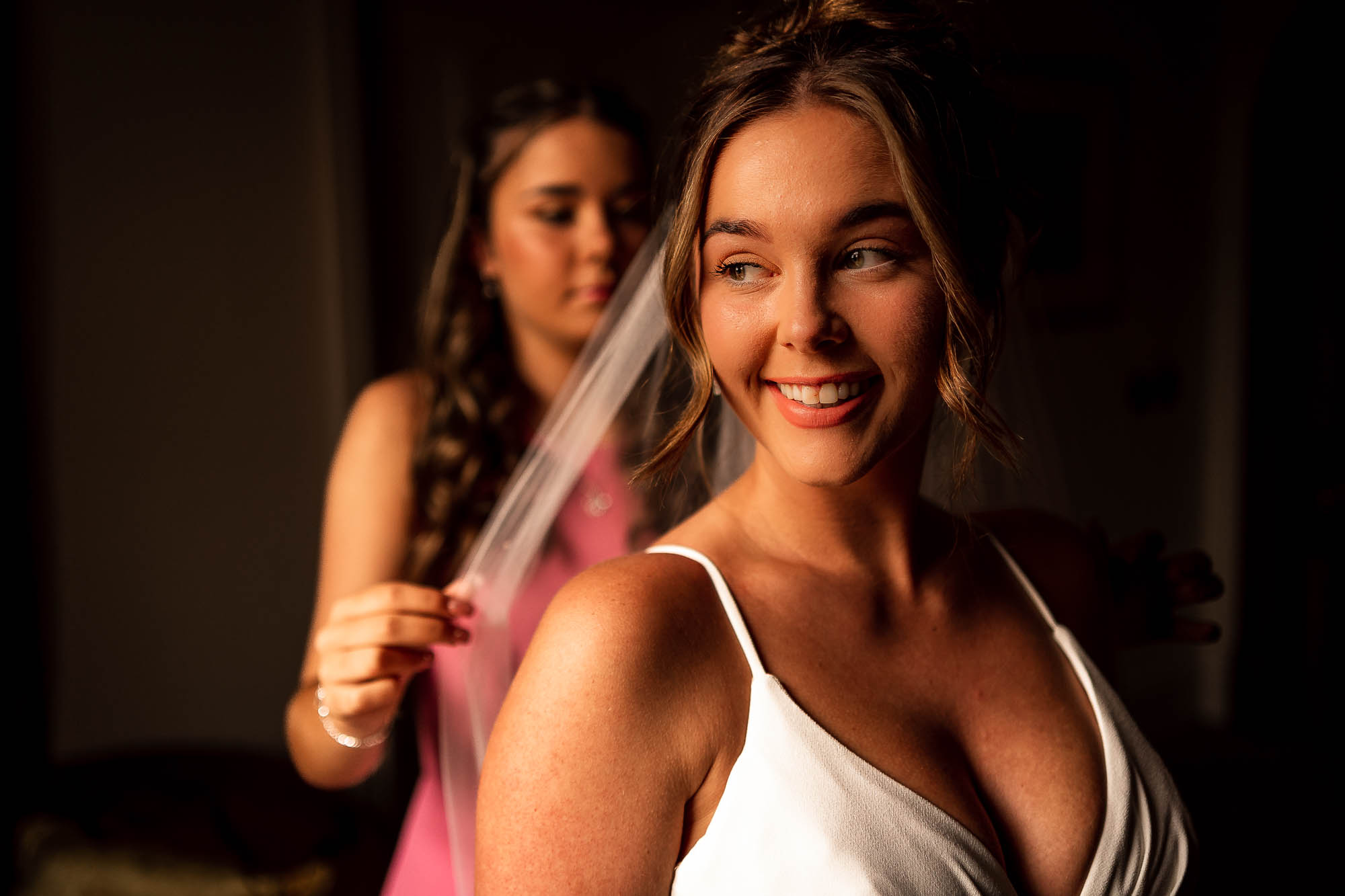 Bridesmaid placing veil on bride