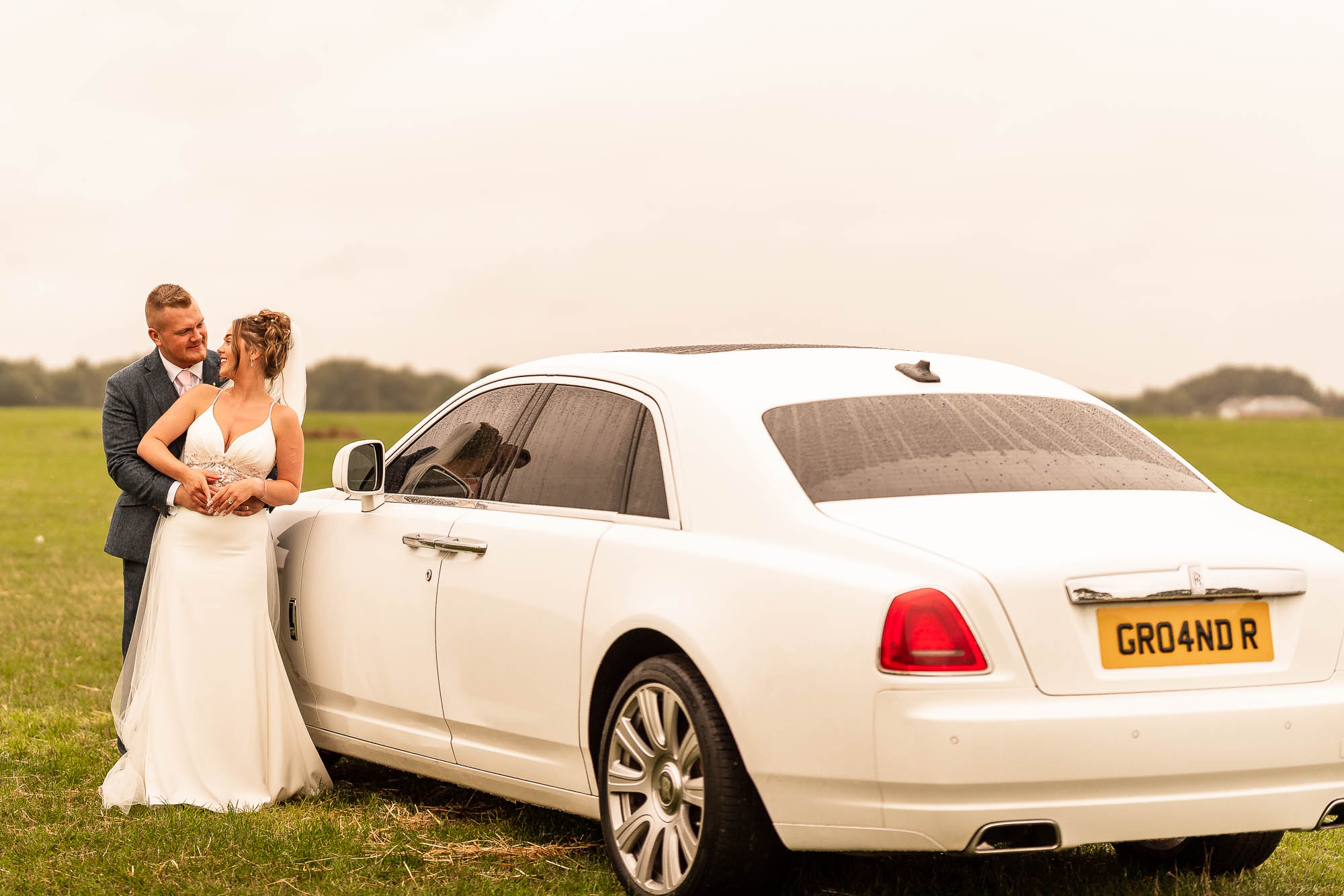 Bride and groom portrait next to wedding car