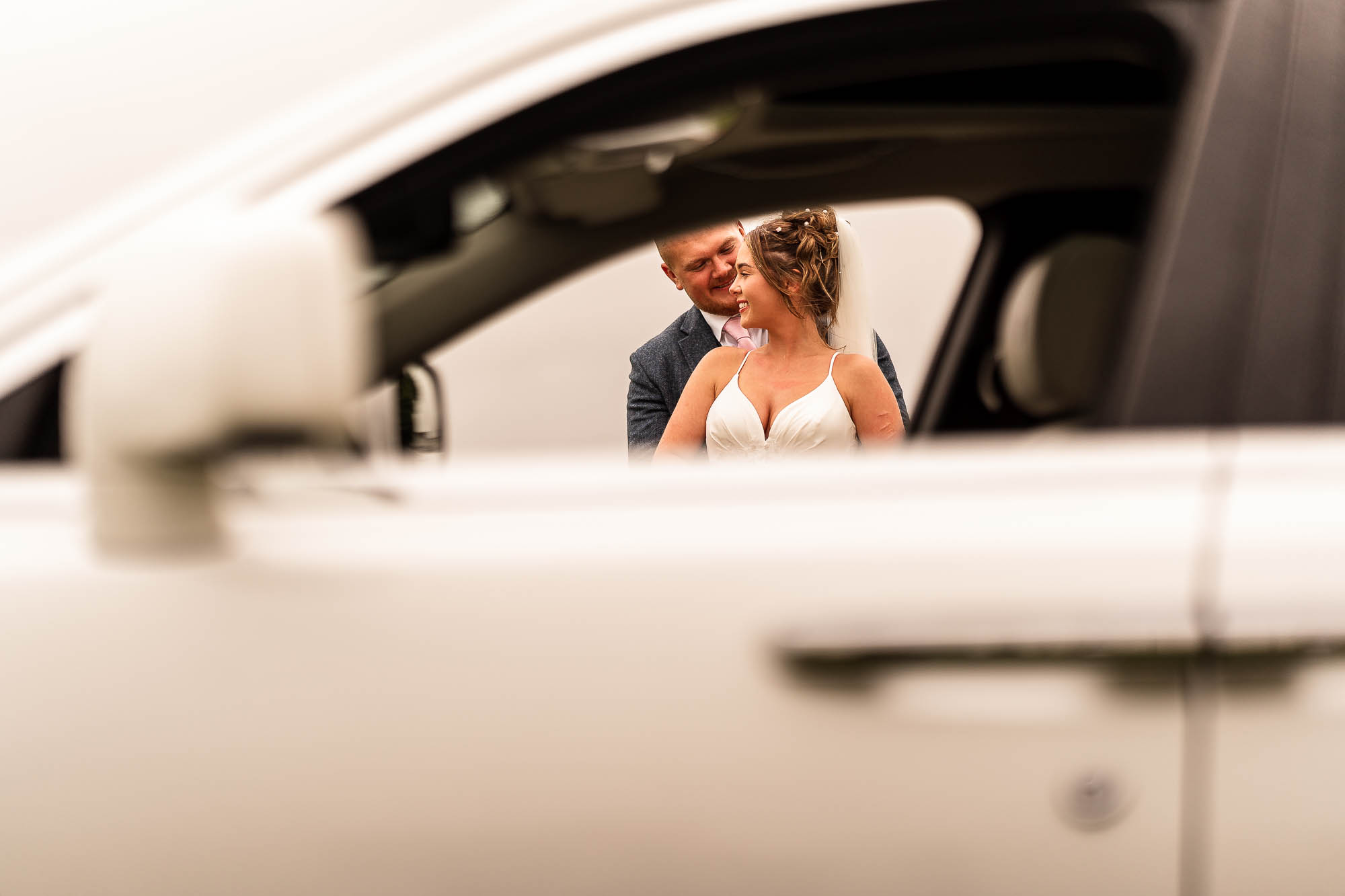 Bride and groom portrait through car window
