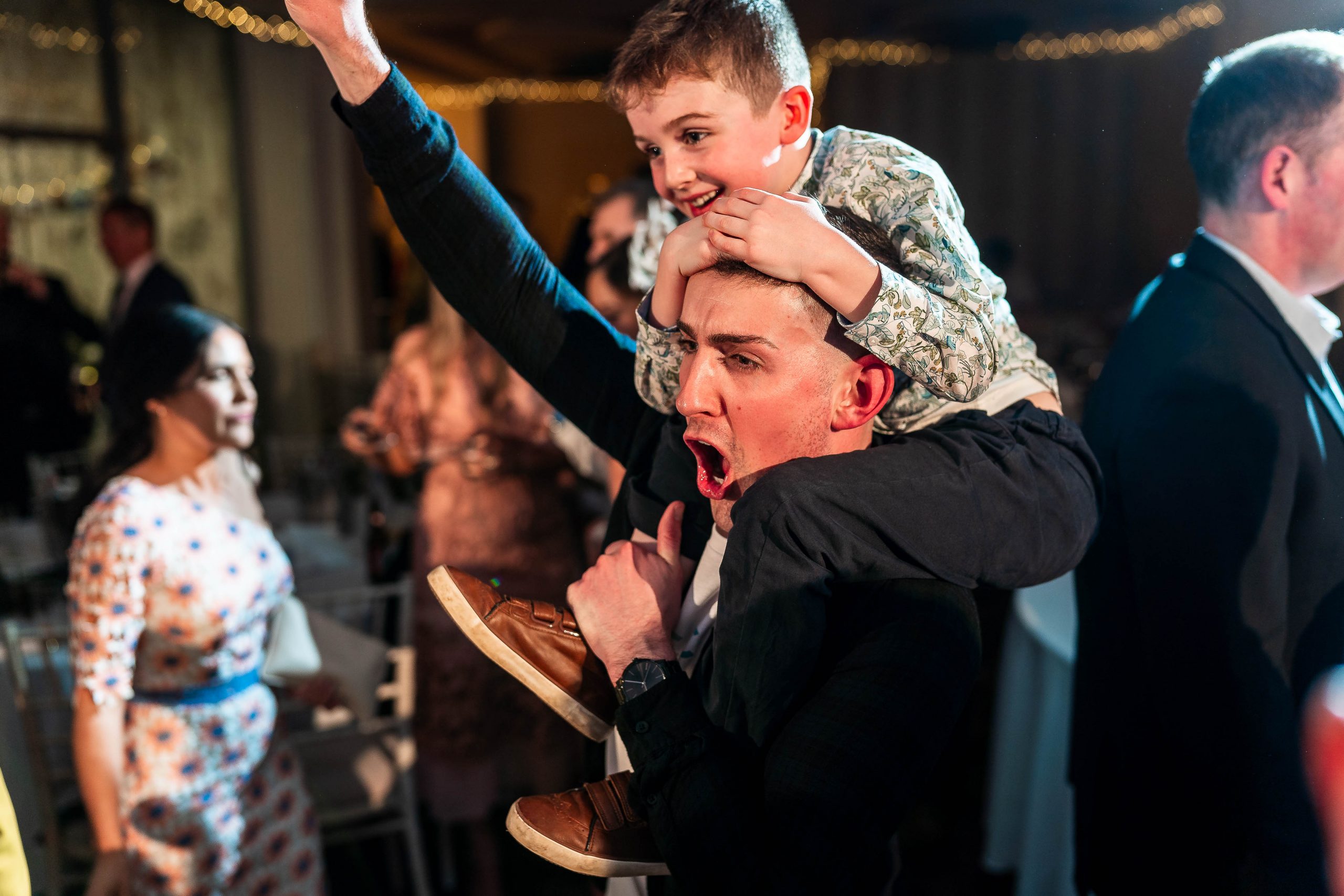 Little boy on dads shoulders on the dance floor