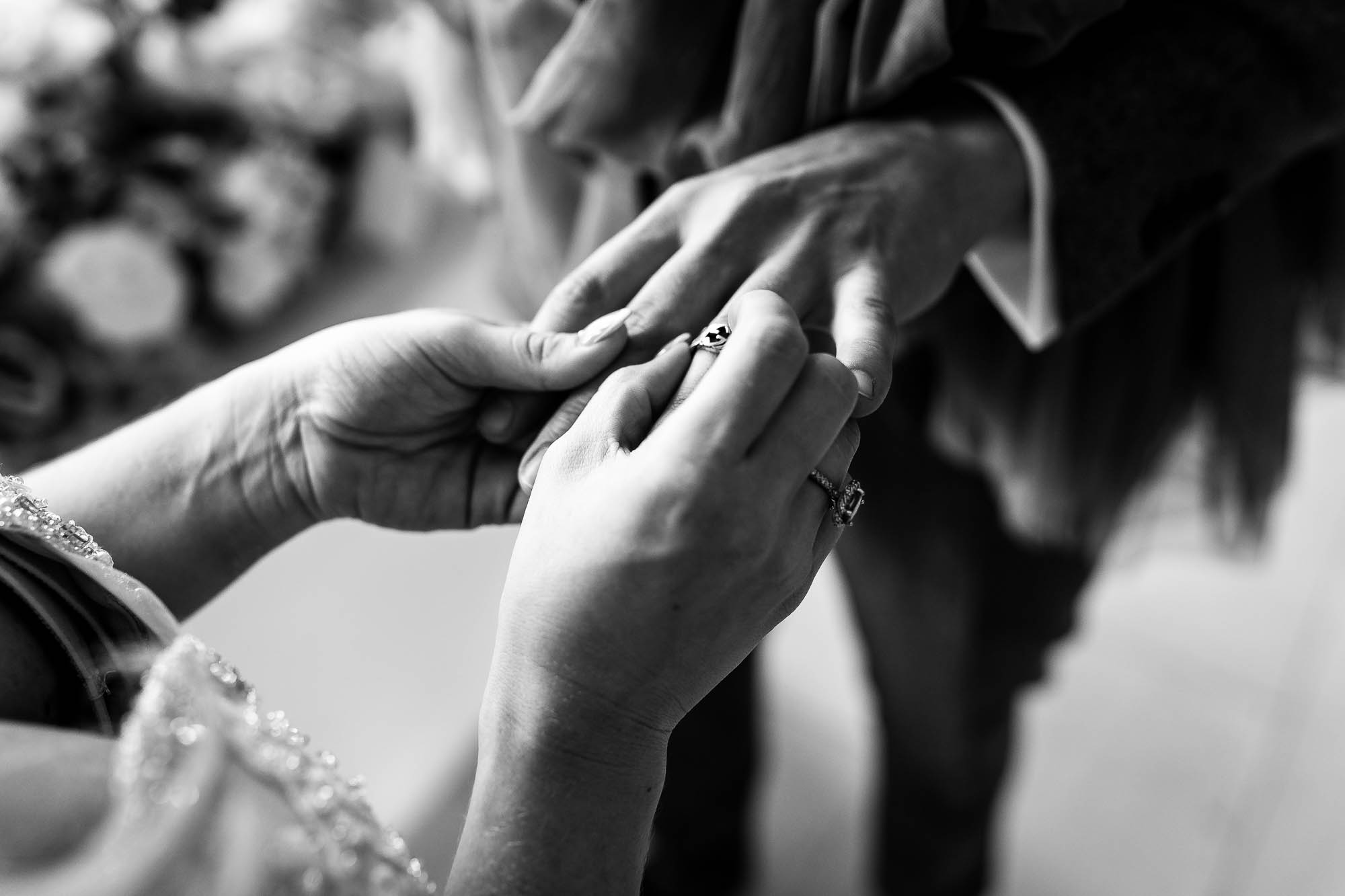 Bride places wedding ring on grooms finger