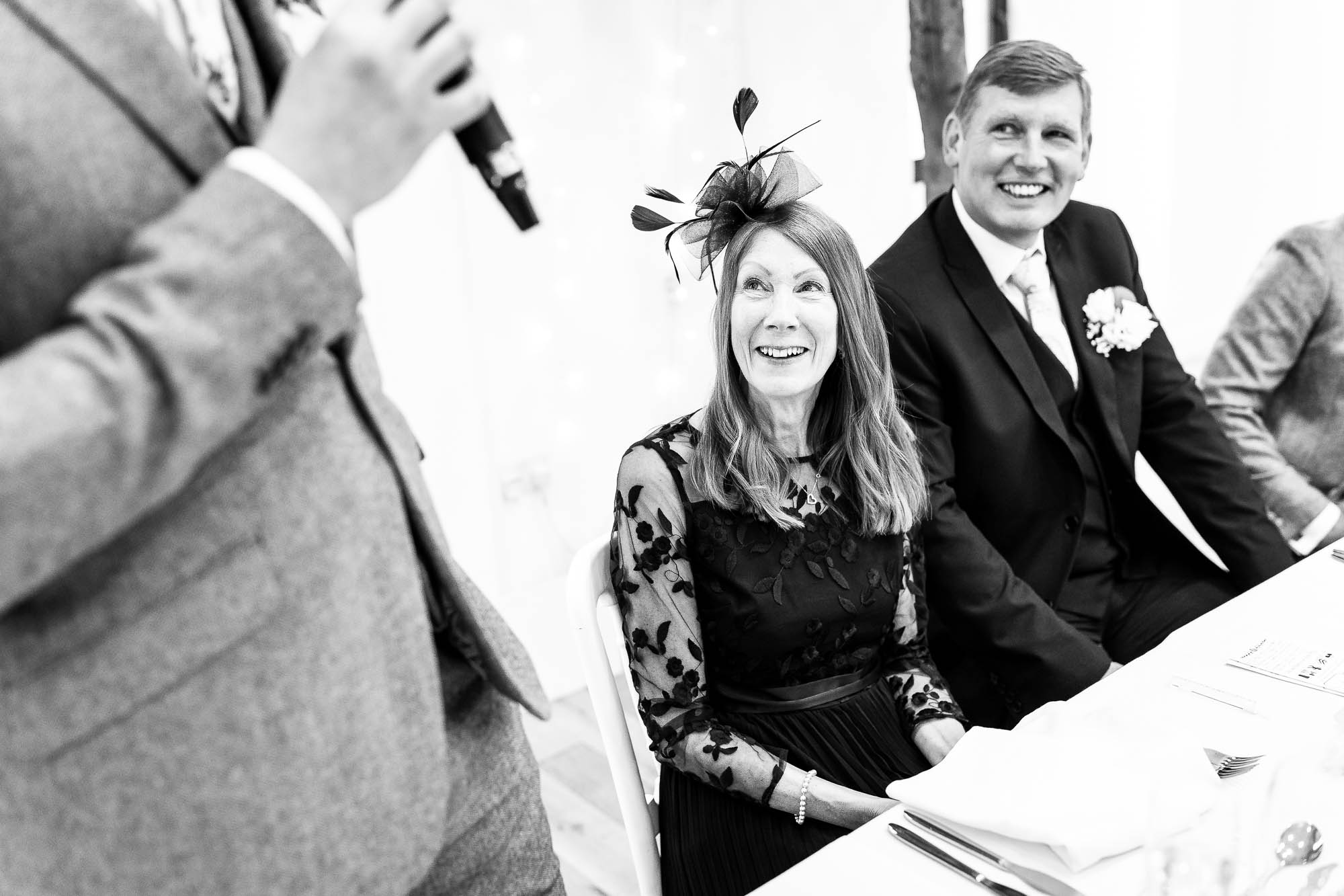 Mother and father of the groom laugh during grooms speech