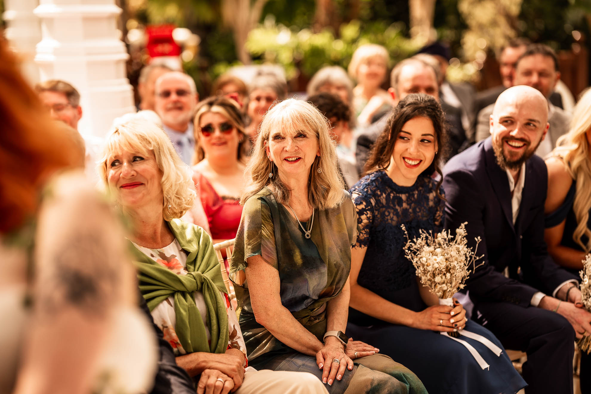 Bridesmaids look on smiling during the vows
