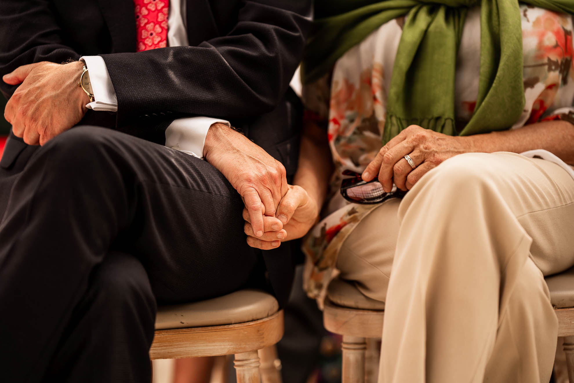 Mother and father of the bride hold hands during the ceremony