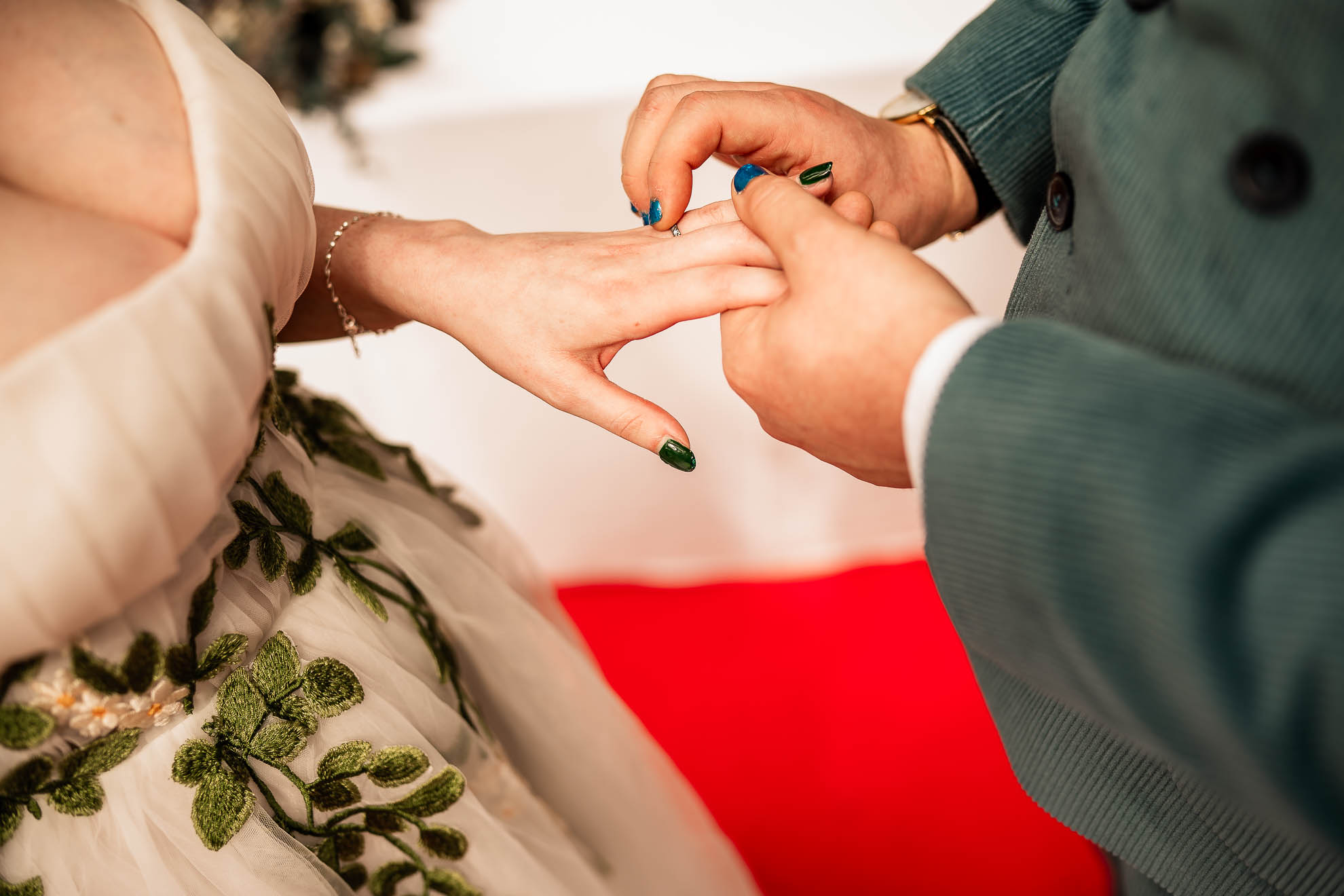 Close up of groom placing wedding ring on brides finger