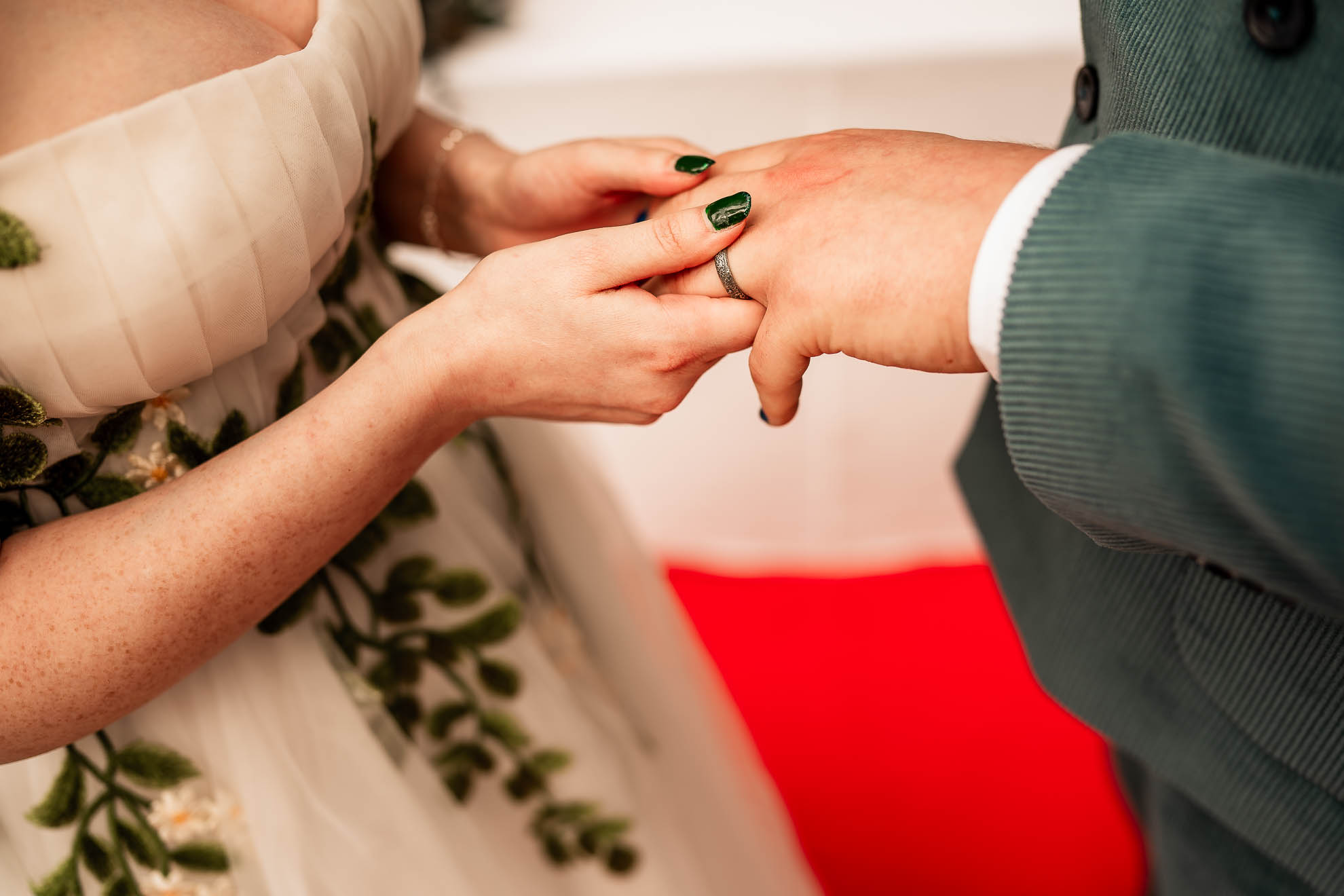 Close up of bride placing wedding ring on grooms finger