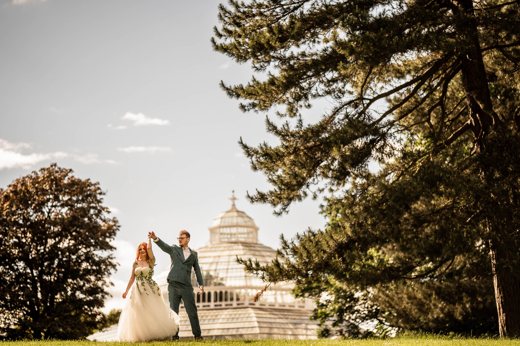 Groom spins bride in front of Palm house
