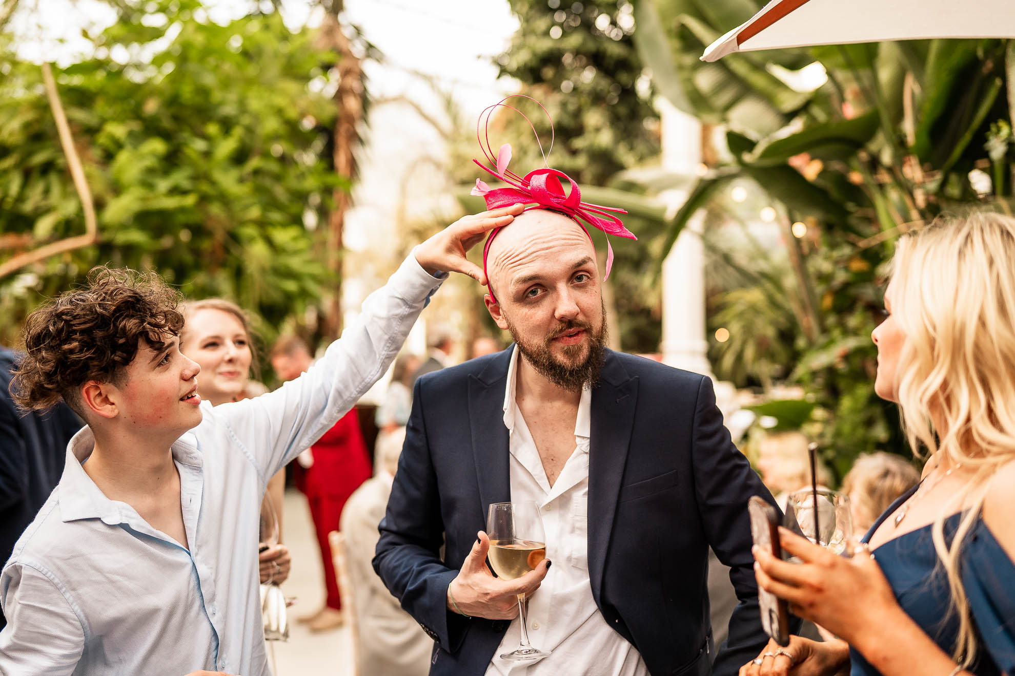 Wedding guest playing with mother of the grooms fascinator
