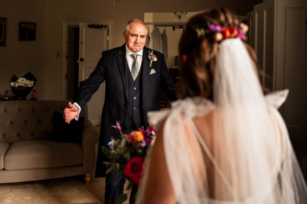 father of the bride with arms outstretched moves to hug the bride