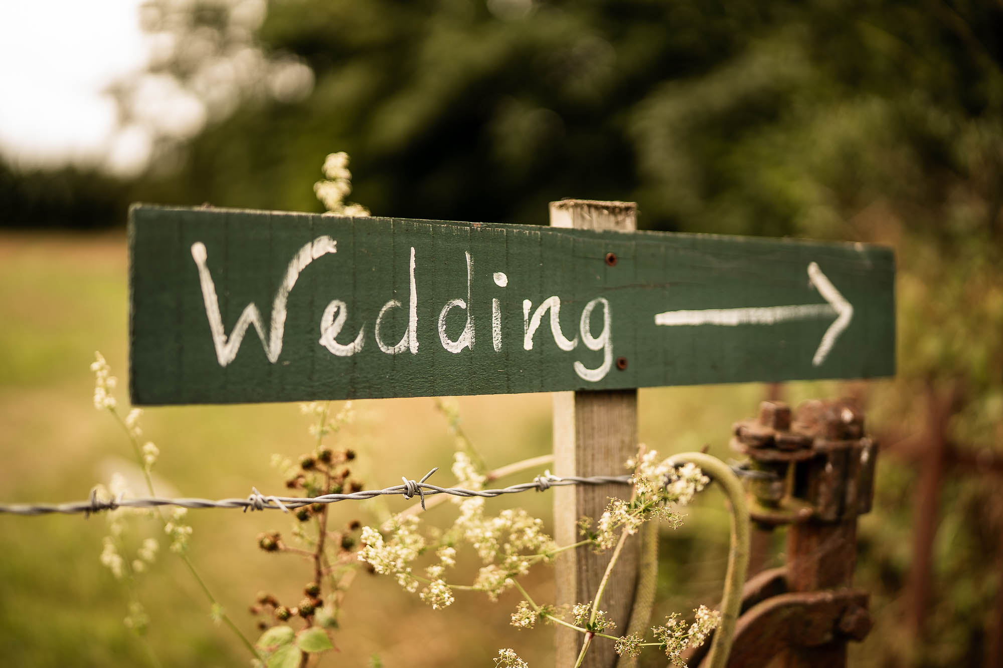 Wooden “Wedding” sign pointing towards ceremony at Wonwood Barton in Devon countryside