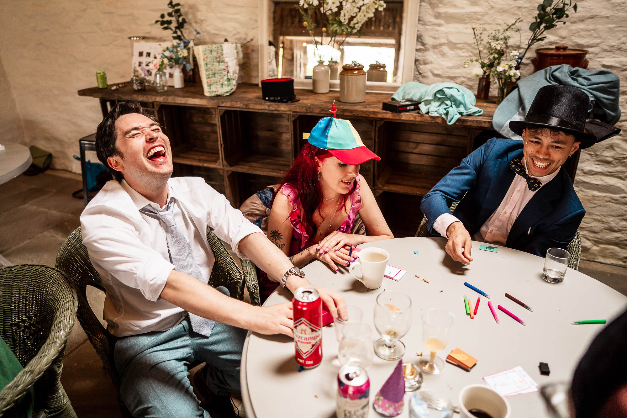 Candid guests in fancy dress hats enjoying evening wedding reception at Wonwood Barton