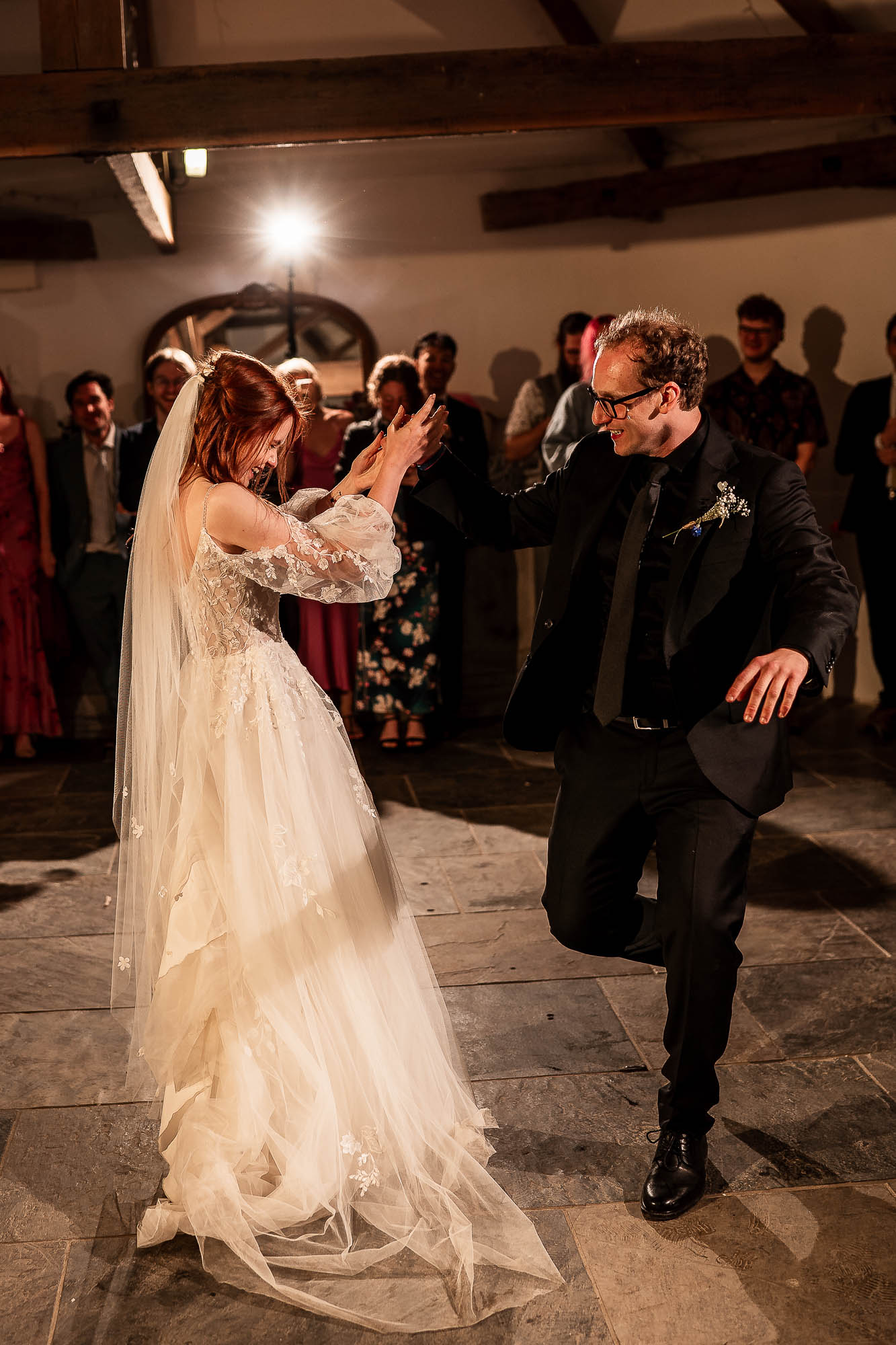 Bride and groom dancing energetically under warm barn lighting at Wonwood Barton