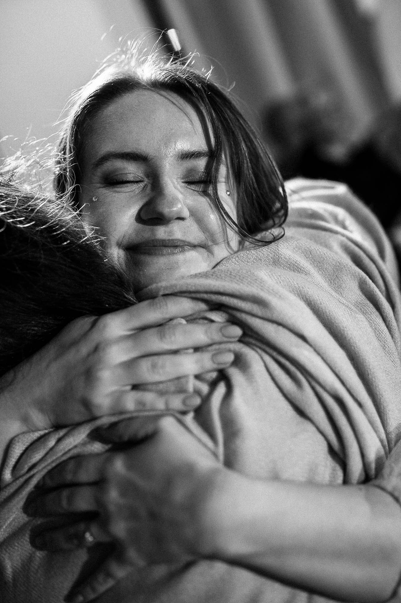 Emotional black and white photo of bride hugging guest during wedding reception