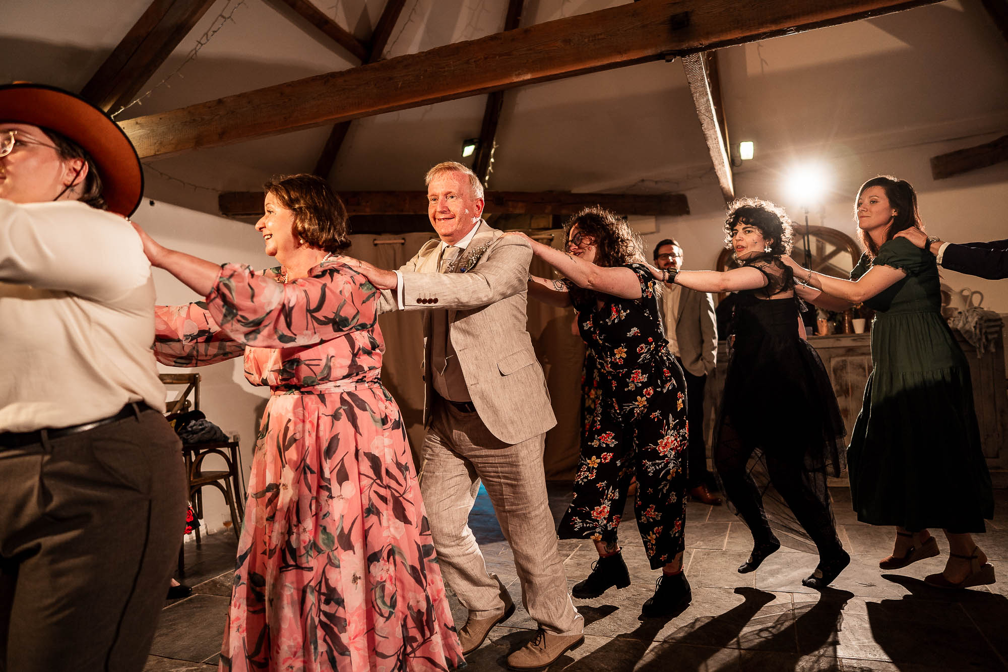 Guests forming conga line on barn dance floor at Wonwood Barton wedding