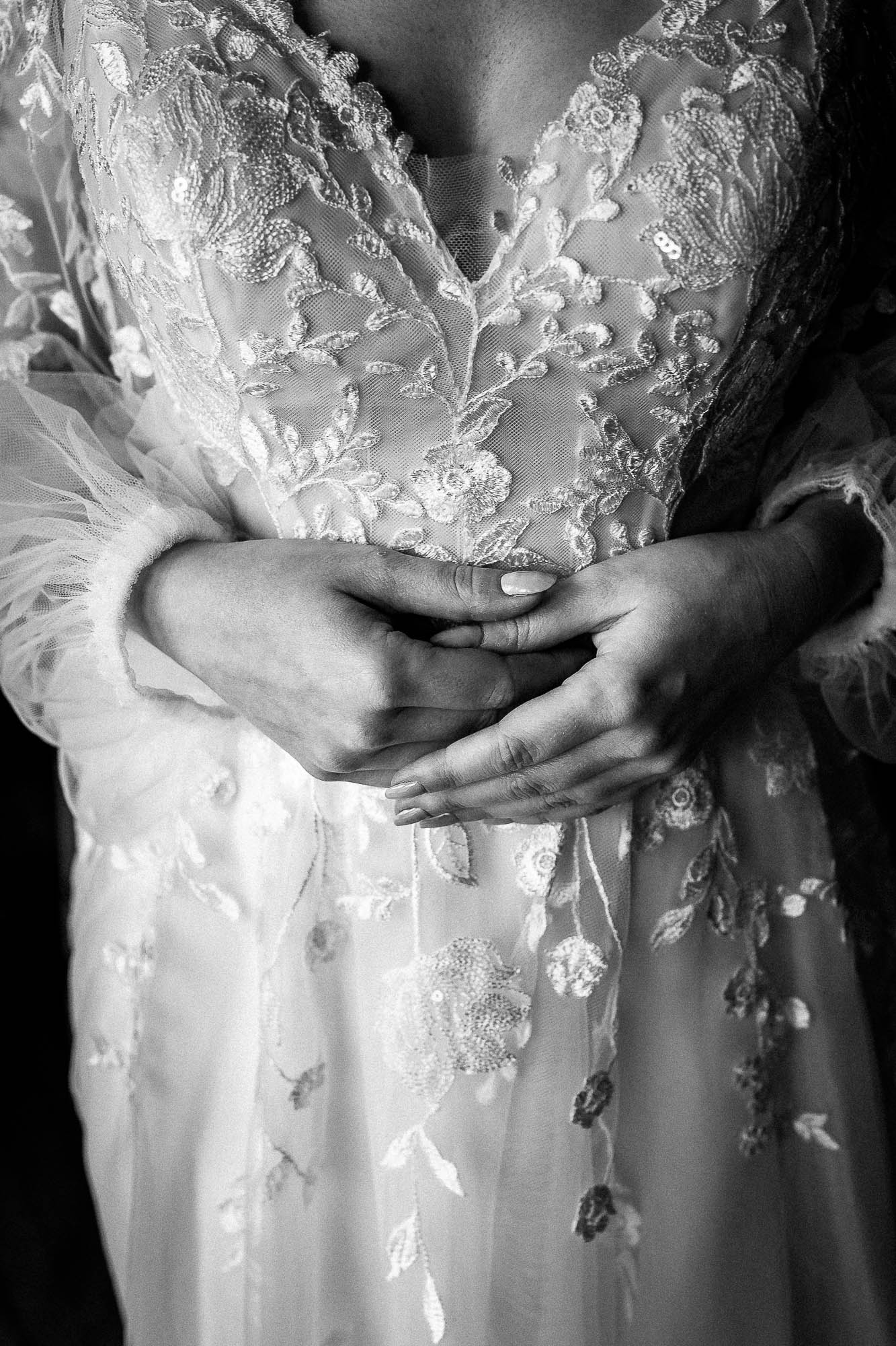 Close-up of bride’s hands resting on detailed lace bodice during bridal prep at Wonwood Barton wedding