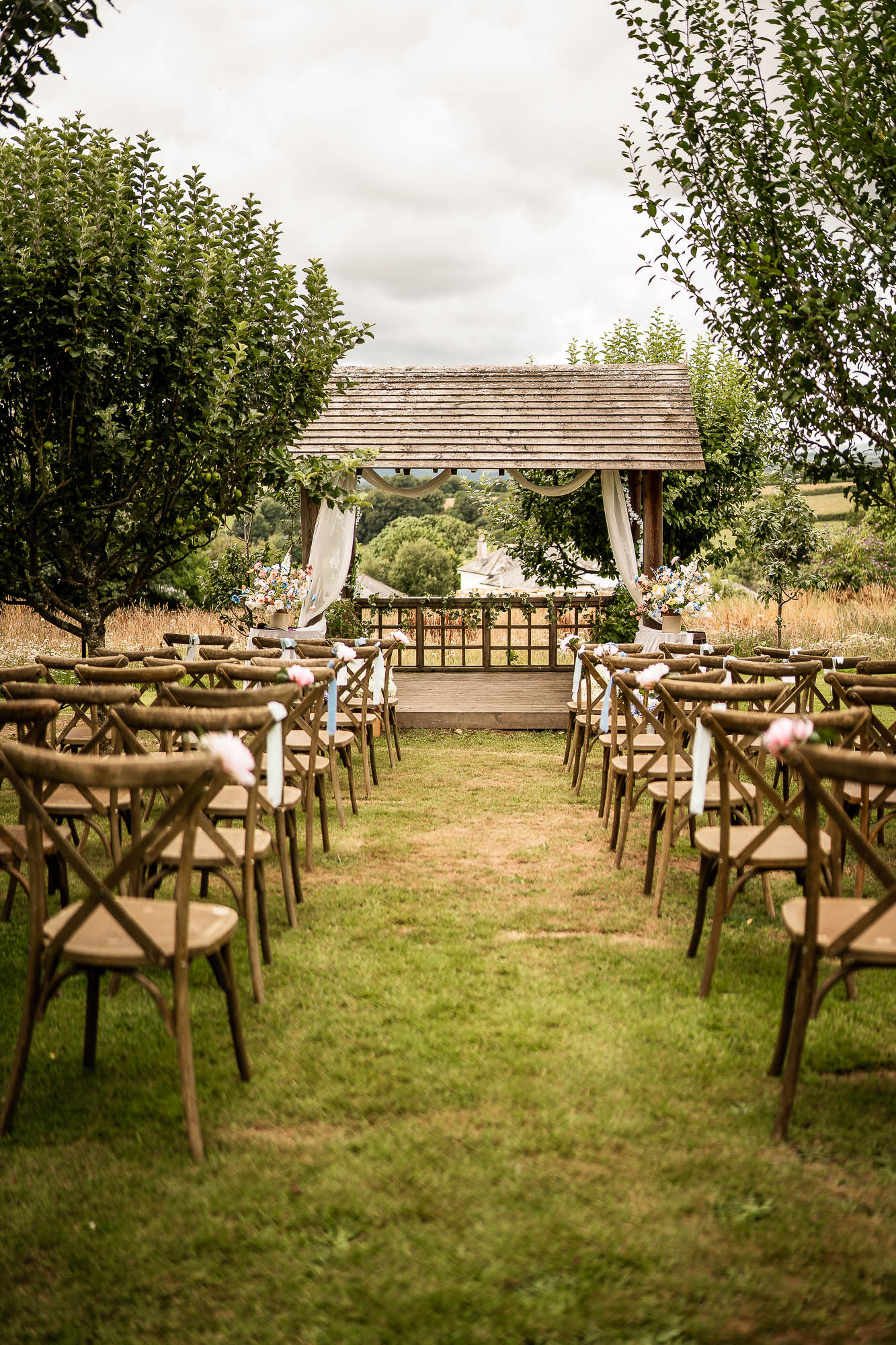 Outdoor wedding ceremony setup with wooden chairs and gazebo at Wonwood Barton Devon