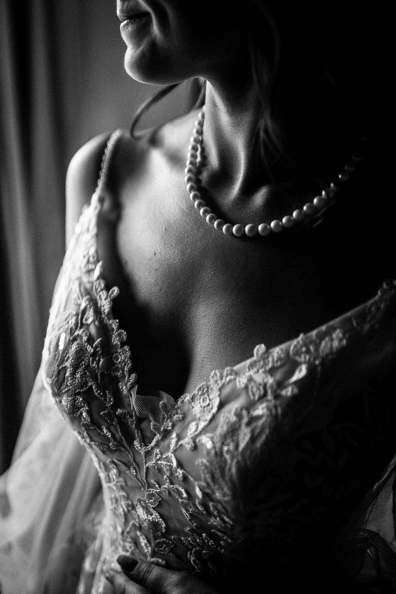 Bridal portrait with pearl necklace and lace bodice in natural window light at Wonwood Barton