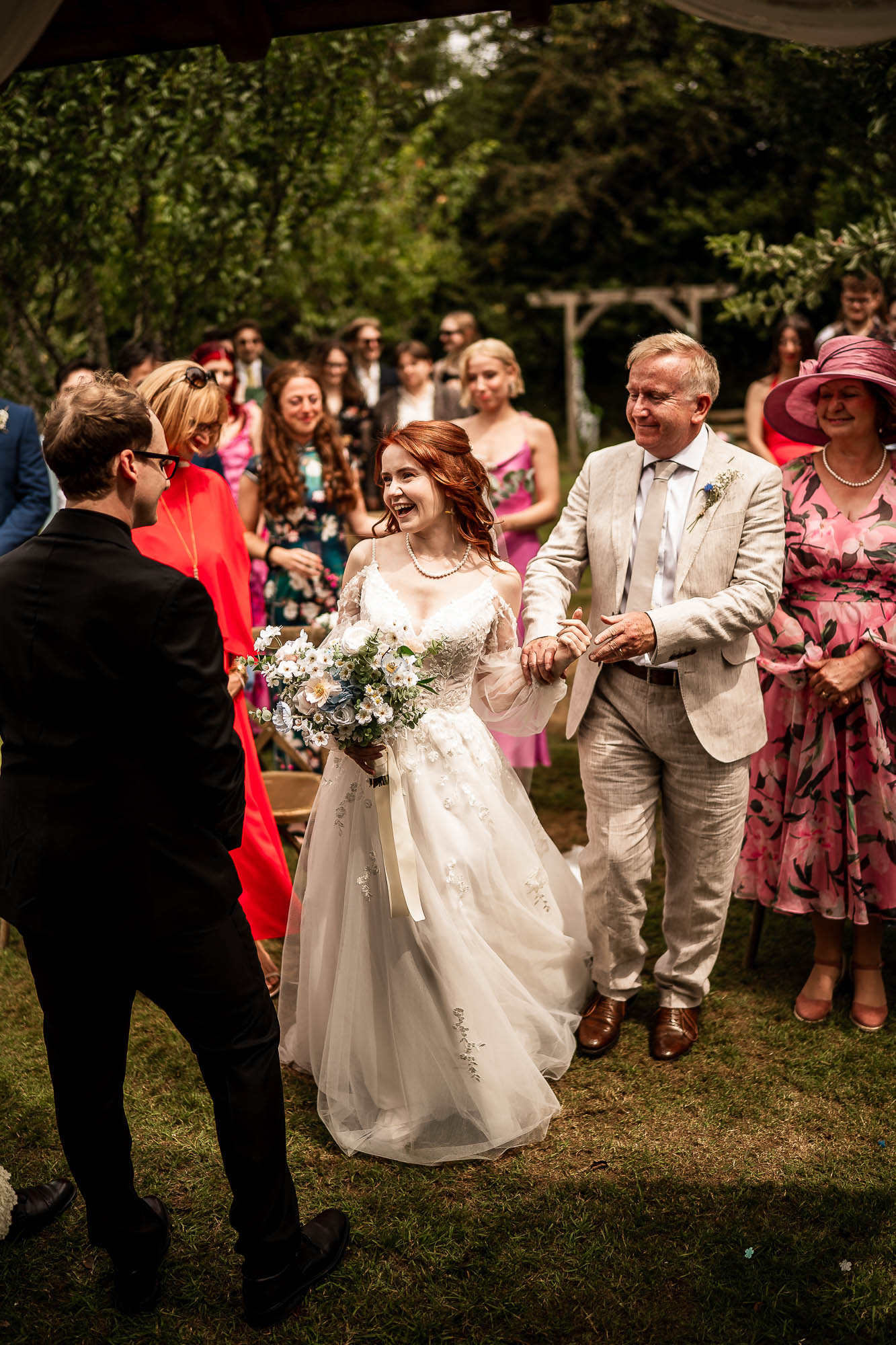 Bride laughing as she reaches groom during outdoor ceremony at Wonwood Barton