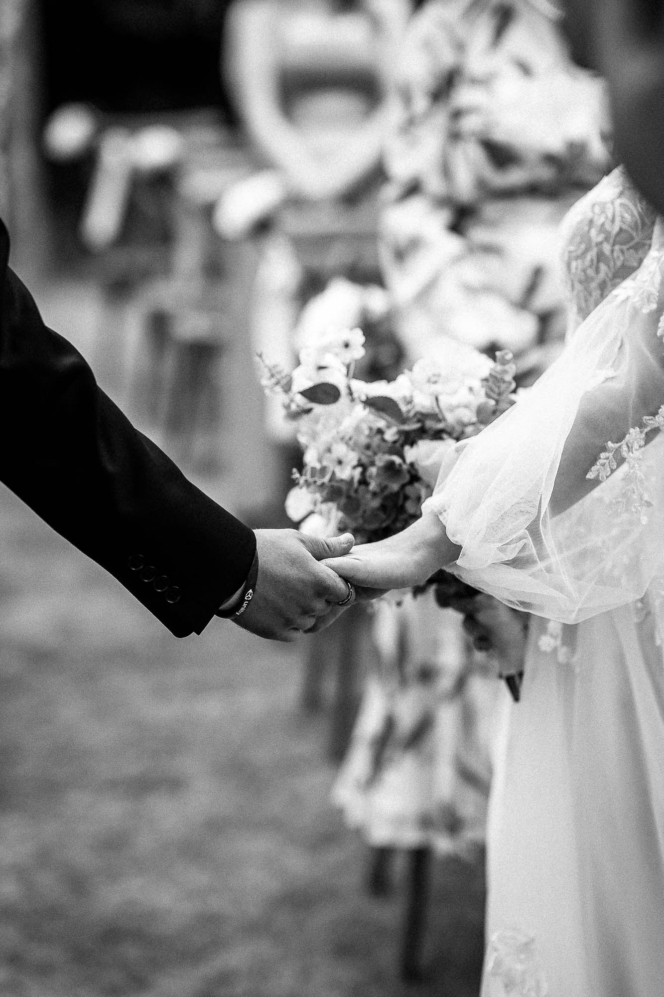 Black and white photo of couple holding hands during wedding vows at Wonwood Barton