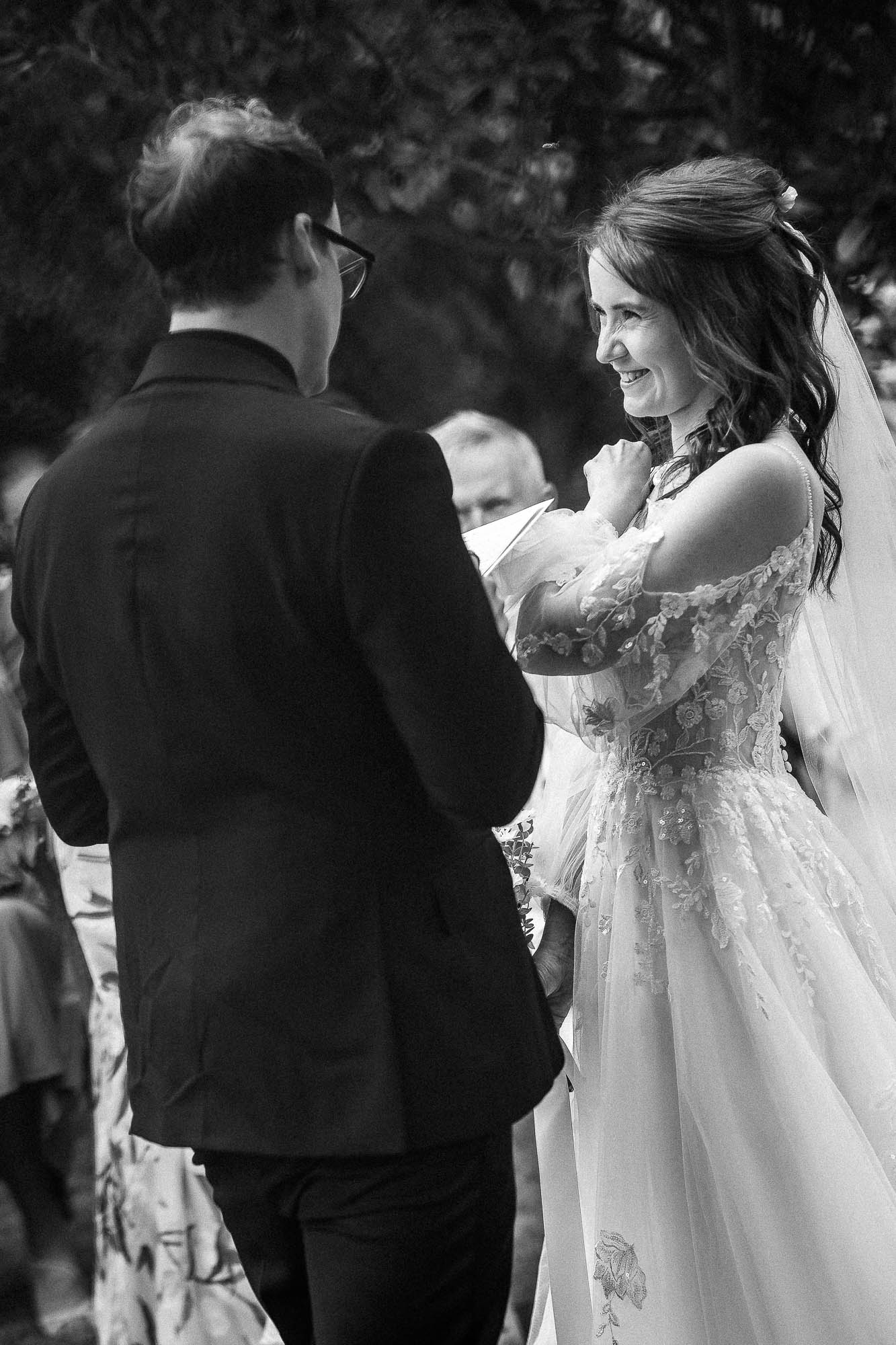 Black and white photo of bride smiling during wedding vows at Wonwood Barton