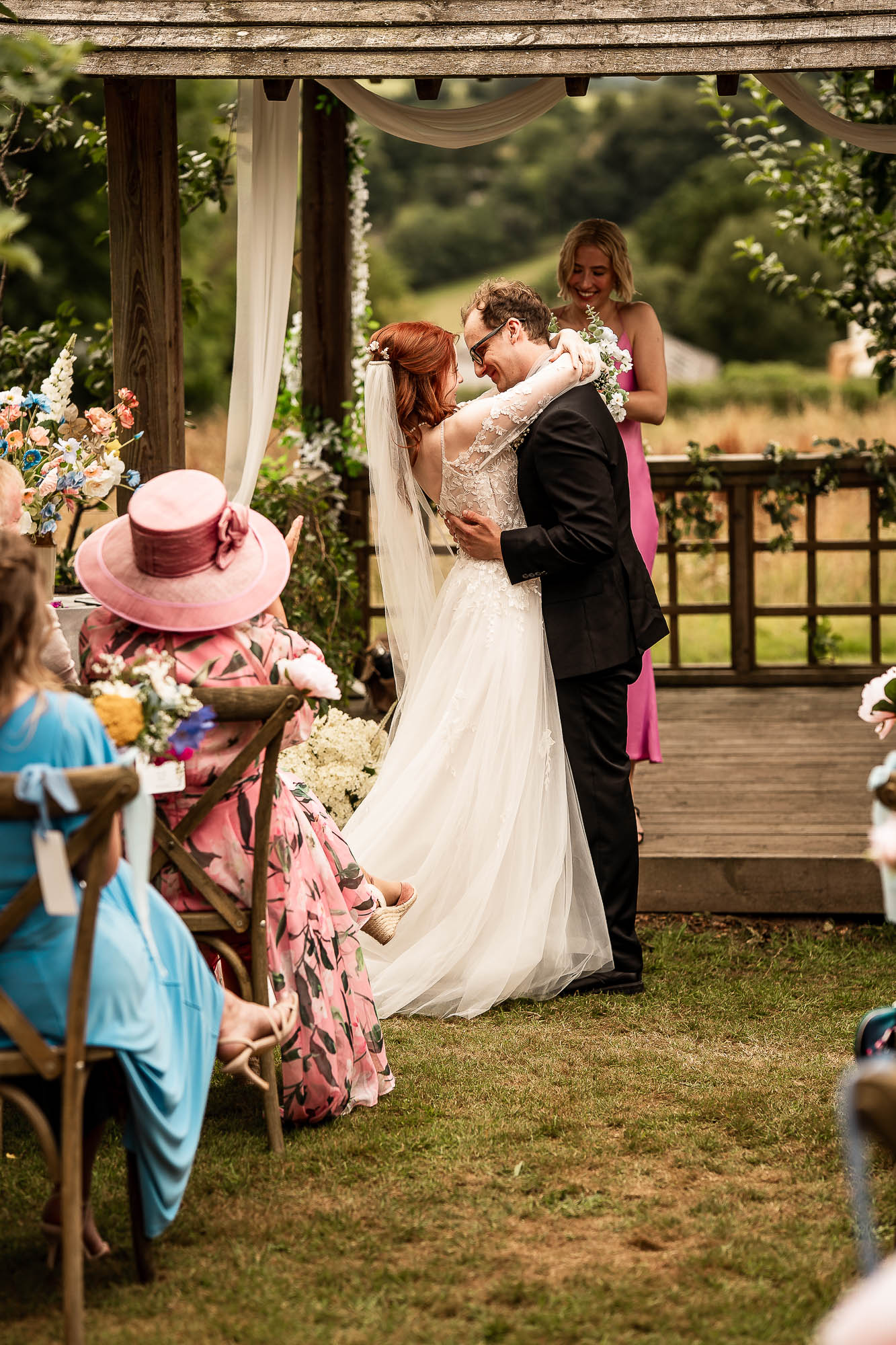 Bride and groom embracing under wooden gazebo at Wonwood Barton wedding ceremony