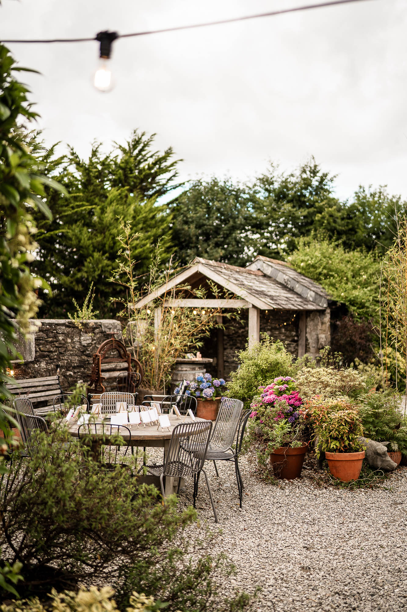 Outdoor courtyard seating area with flowers and string lights at Wonwood Barton