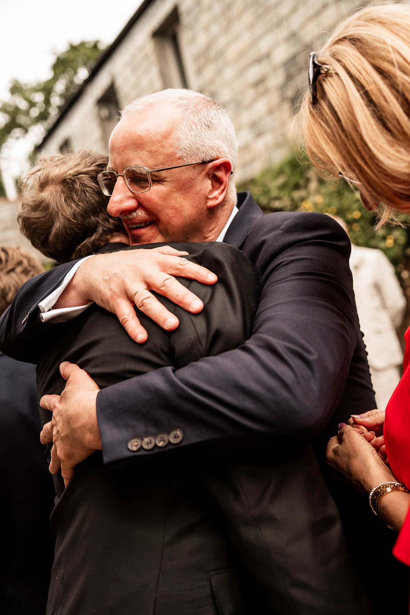 Father of the groom hugging his son during drinks reception at Wonwood Barton wedding in Devon