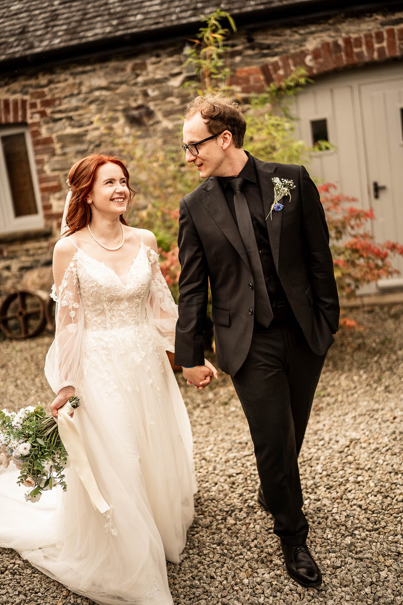 Bride and groom walking hand in hand in the courtyard at Wonwood Barton wedding venue in Devon