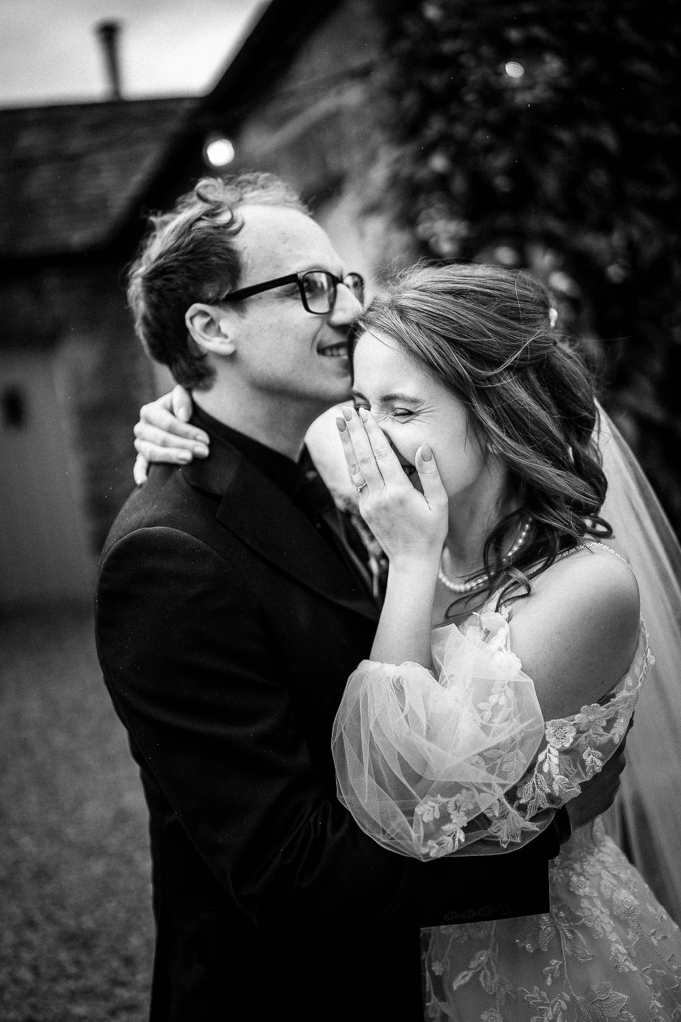 Bride laughing as groom kisses her forehead at Wonwood Barton courtyard wedding