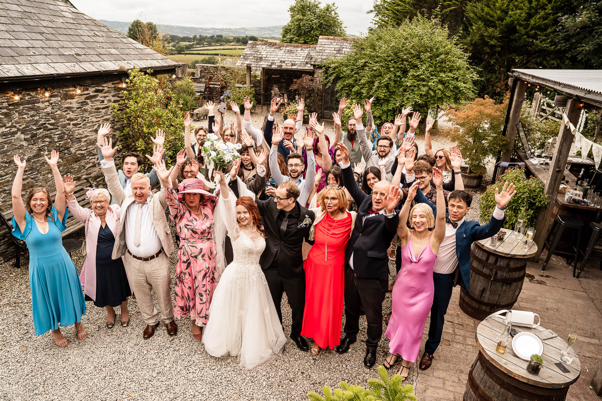 Wedding guests cheering with raised hands in courtyard at Wonwood Barton Devon