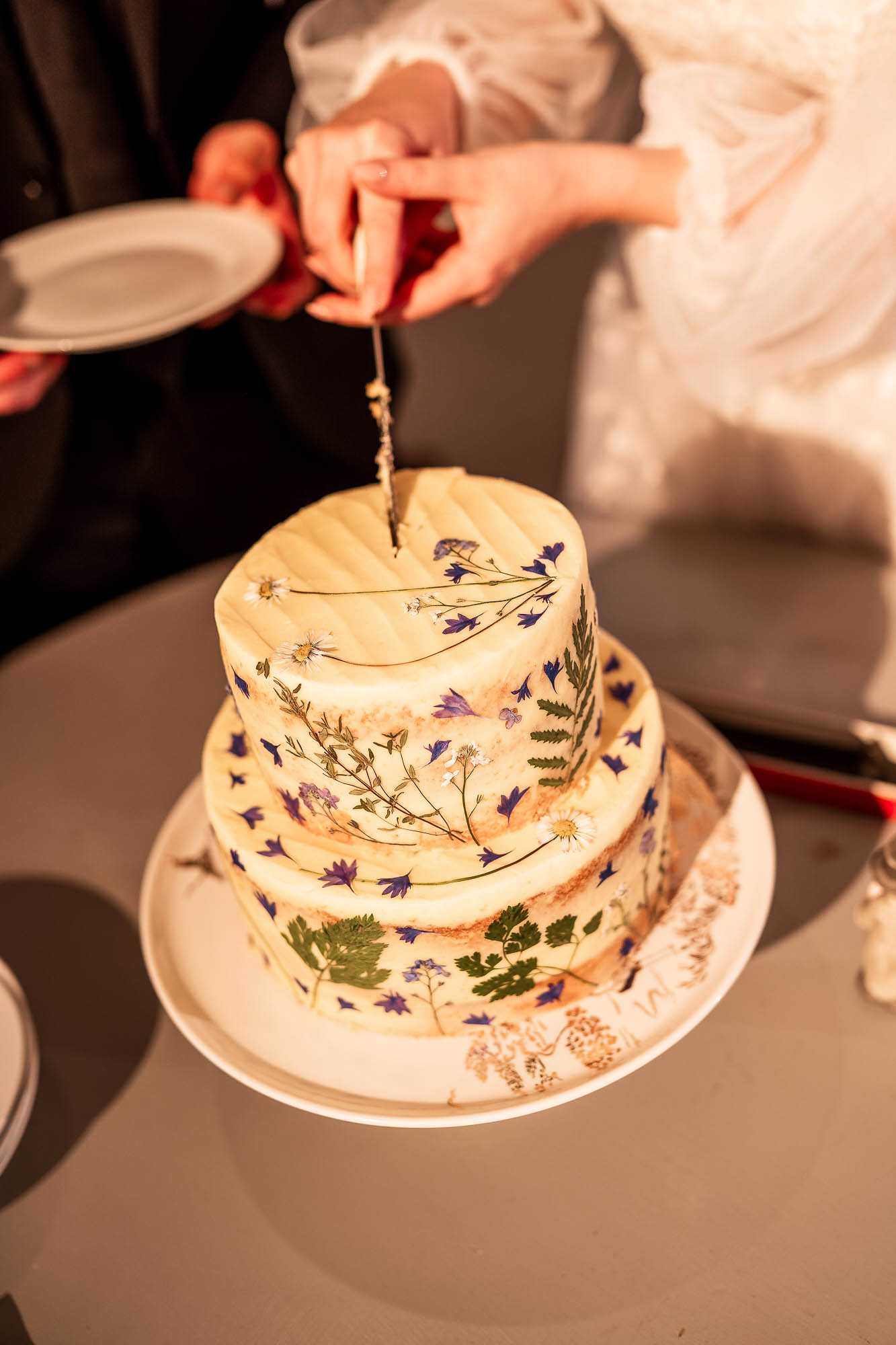 Bride and groom cutting two-tier floral wedding cake at Wonwood Barton reception