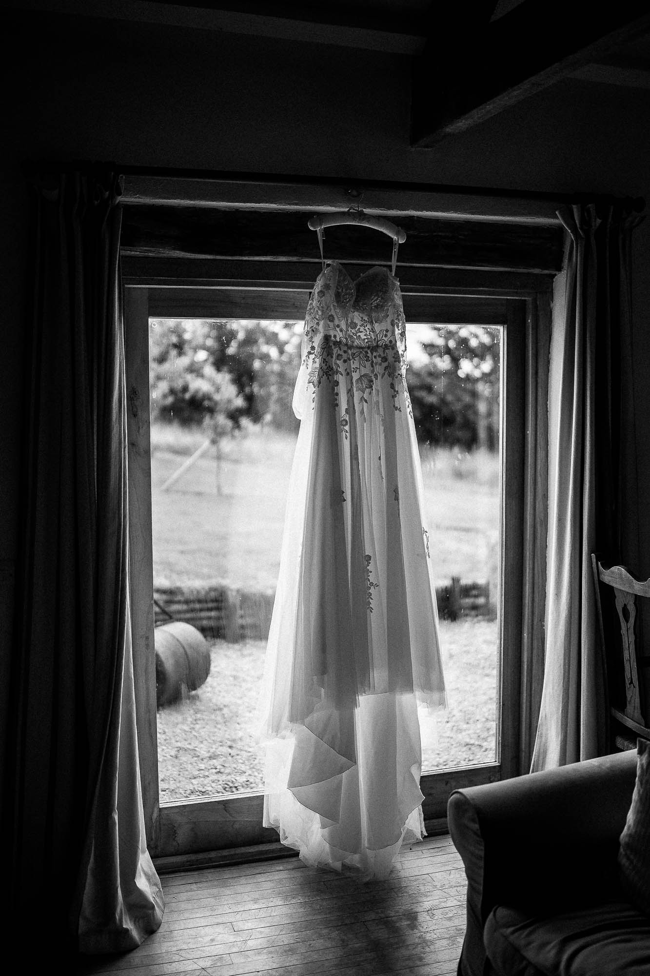 Bride’s wedding dress hanging in window light at Wonwood Barton