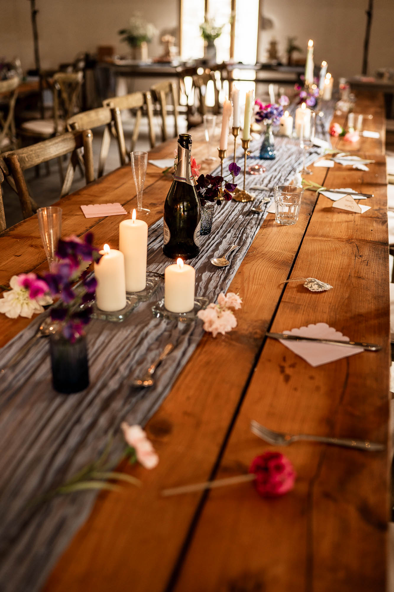 Rustic wooden wedding breakfast table with candles and wildflowers at Wonwood Barton Devon